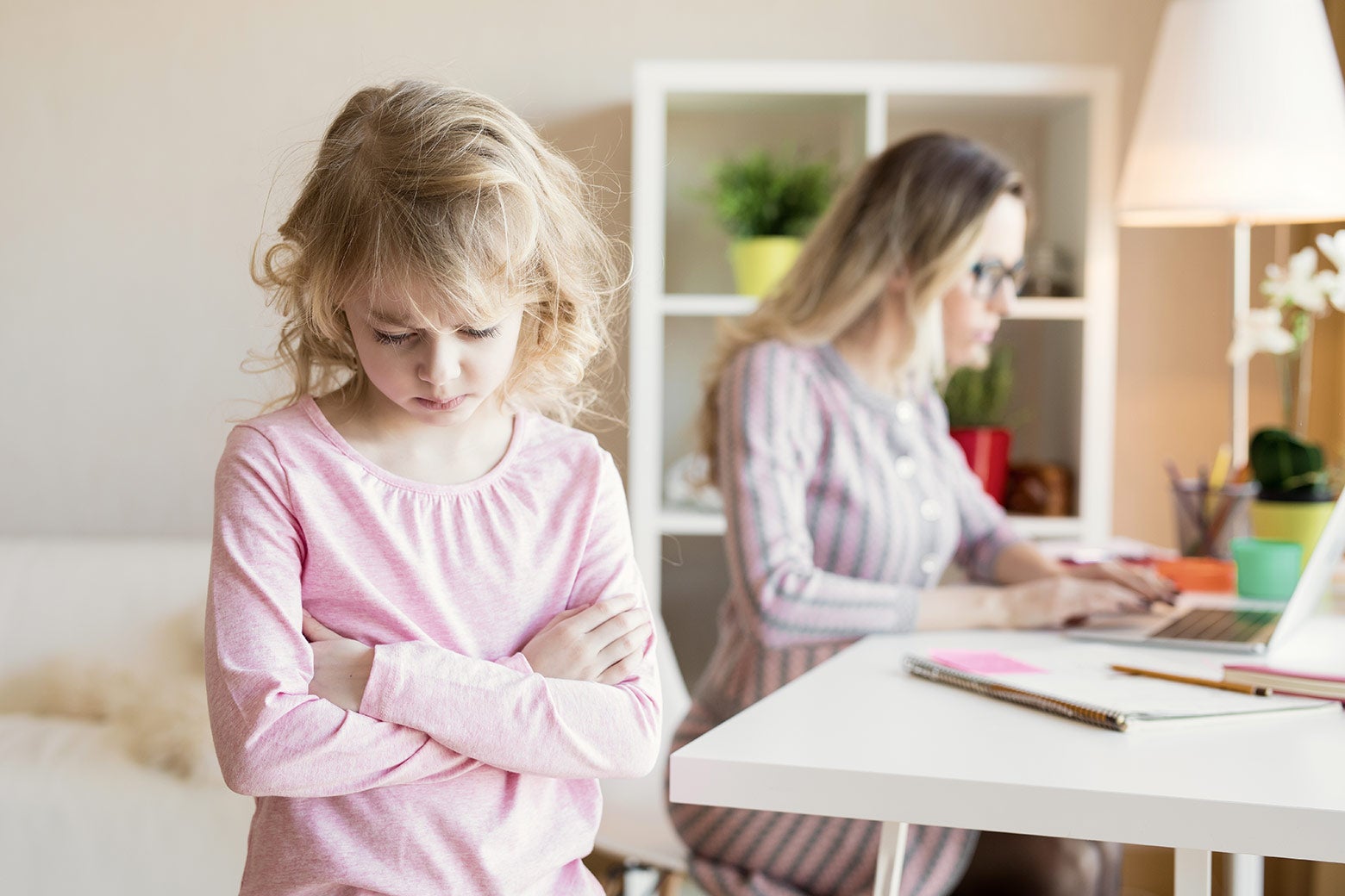 A child frowns while her mom blogs about her frowning.