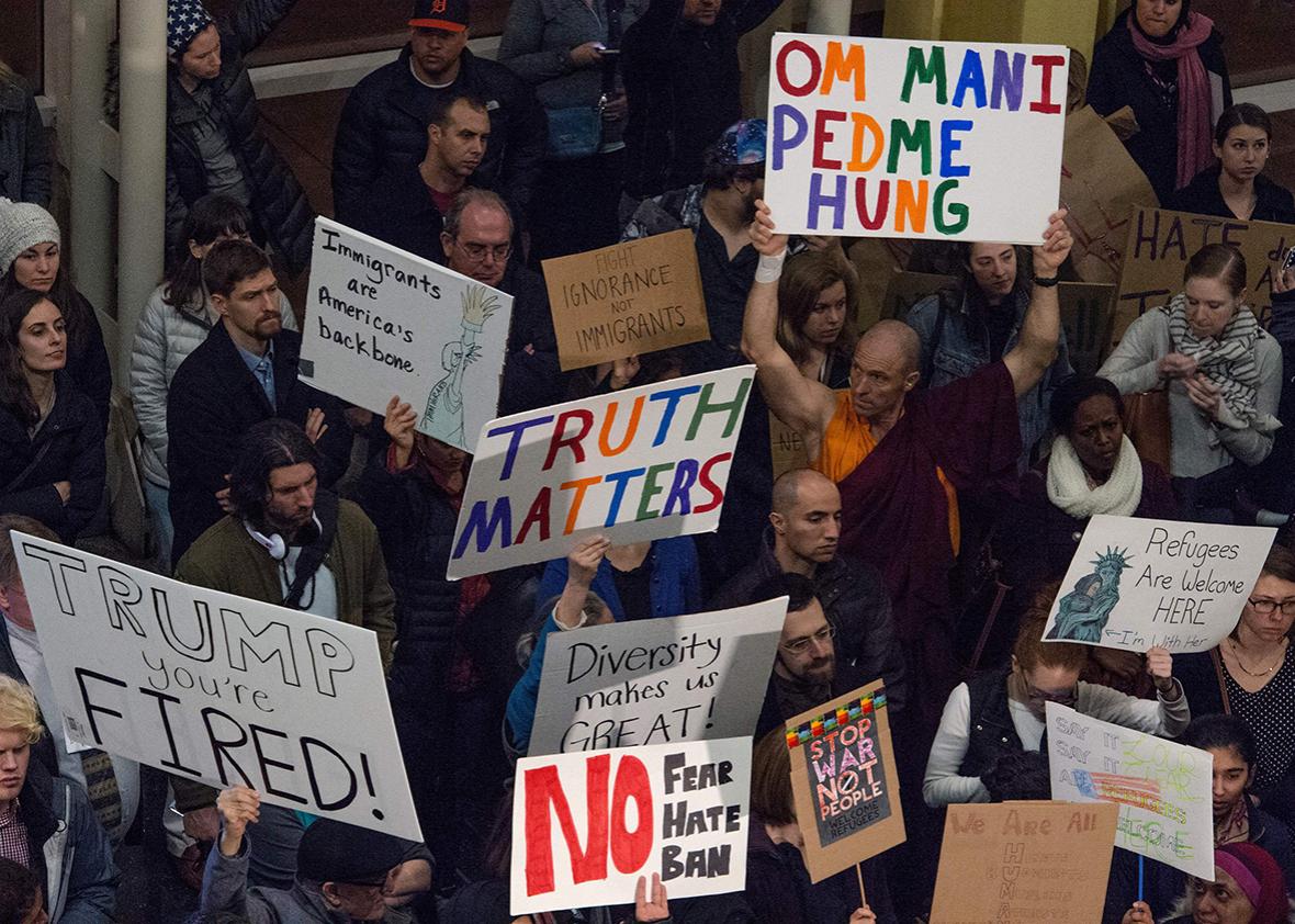 People hold up signs during a protest against US President Donald Trump's immigration rules at the Reagan National Airport in Arlington, Virginia on February 1, 2017.