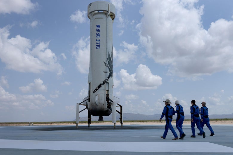 Blue Origin’s New Shepard crew walk near the booster.