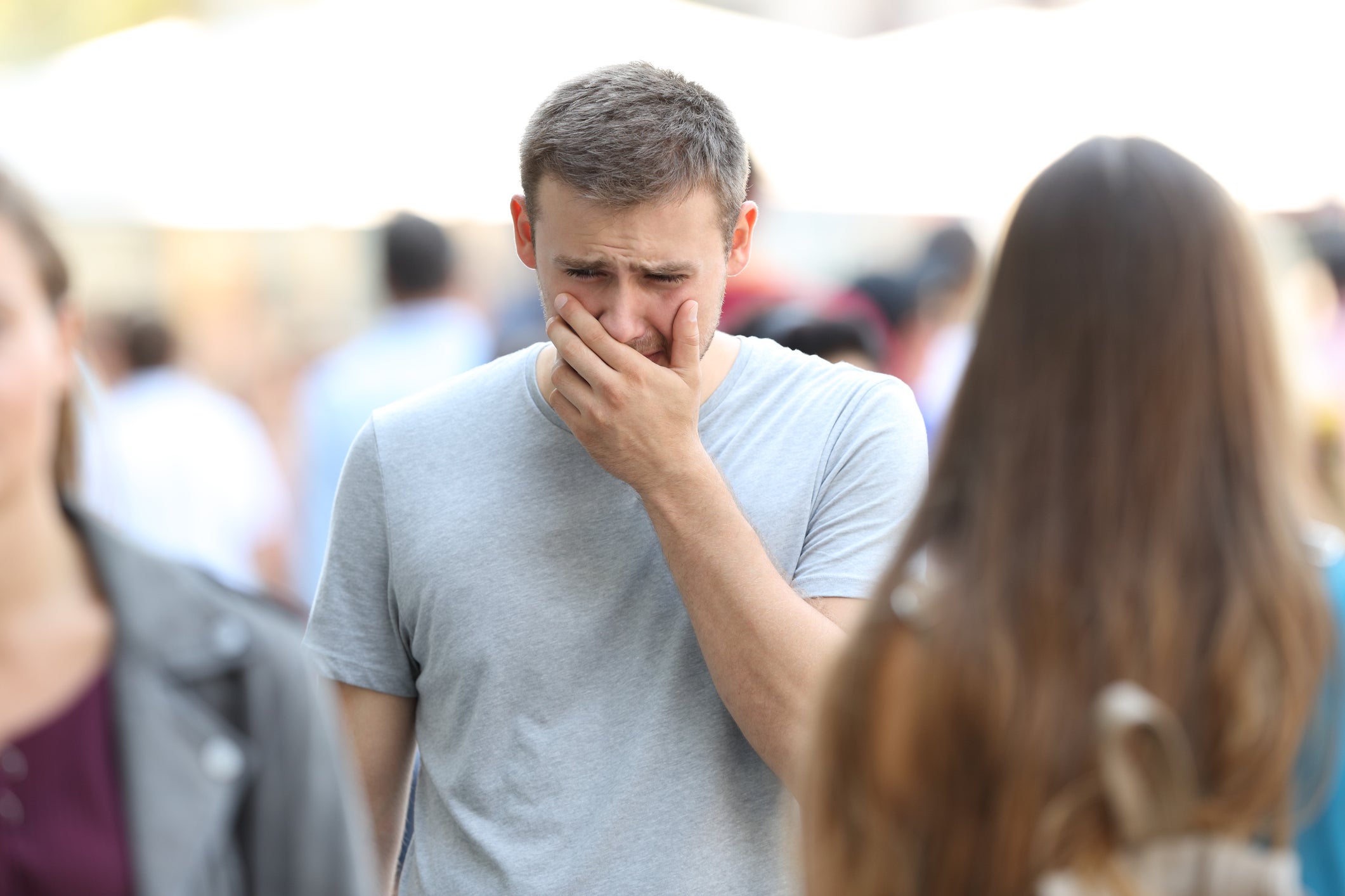 A man crying in the middle of a crowded sidewalk.