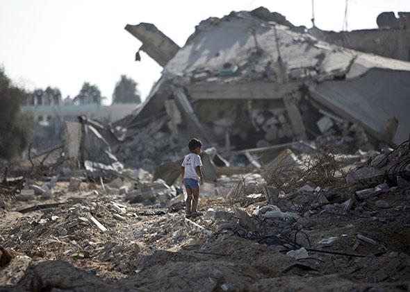 A Palestinian boy walks over debris as civilians who were displaced due to fighting between Israel’s army and Hamas fighters return to check their homes in Gaza City’s Shejaiya neighborhood, on Aug. 1, 2014.