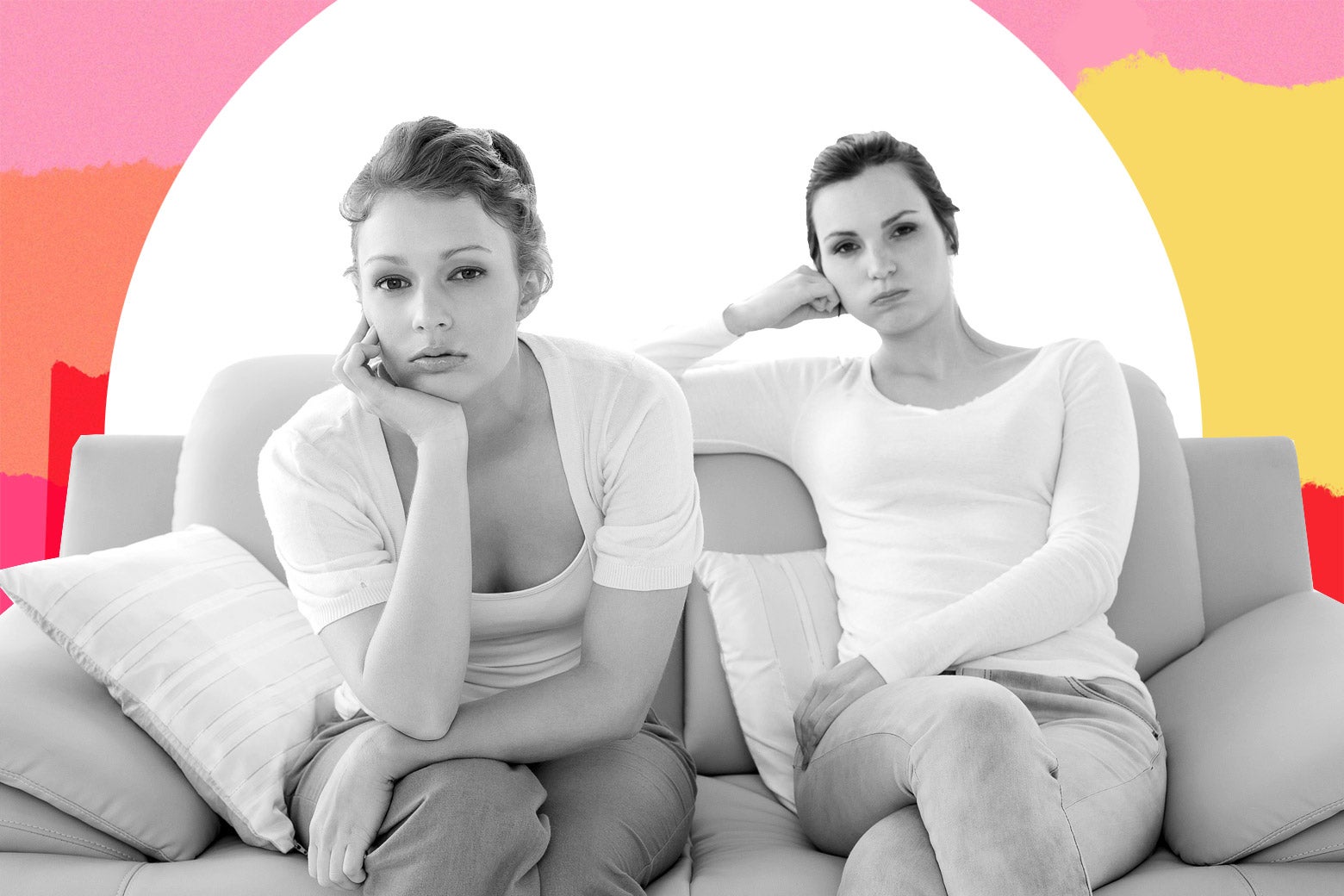 Two young women sitting on the couch looking directly at the camera as if they are fed up.