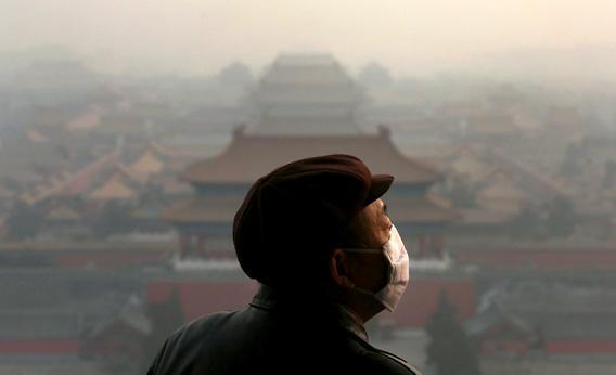 A tourist wearing a mask looks at the Forbidden City as pollution covers the city on Wednesday in Beijing, China. 