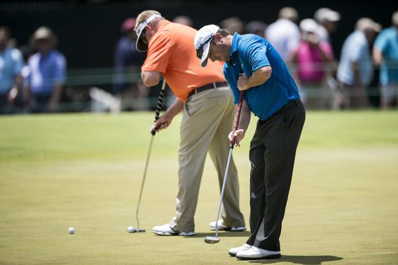Tim Clark (R) of South Africa uses an anchored putter during practice before the US Open at Merion Golf Club