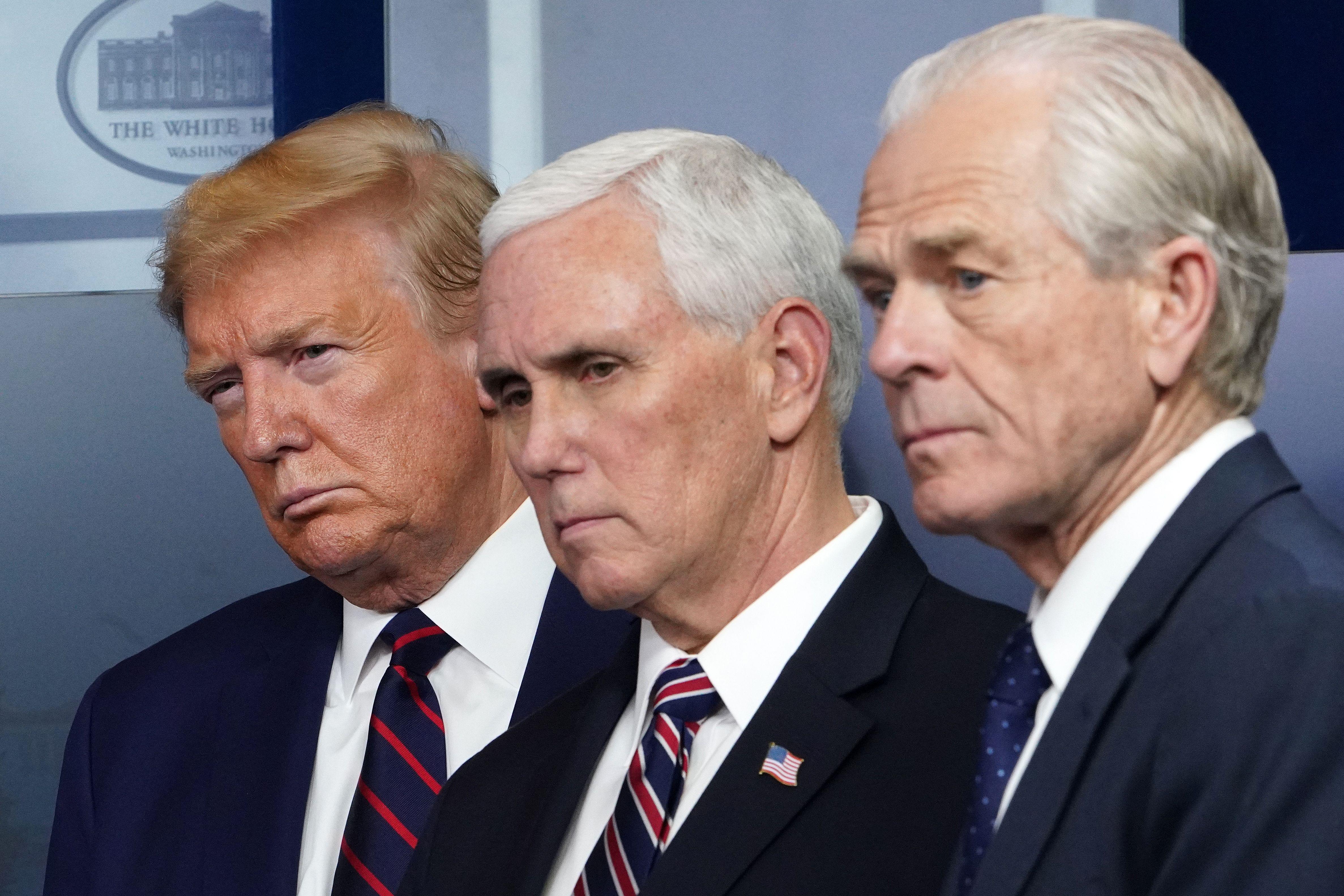 Donald Trump, Mike Pence, and Peter Navarro, all wearing suits, look in the same direction.