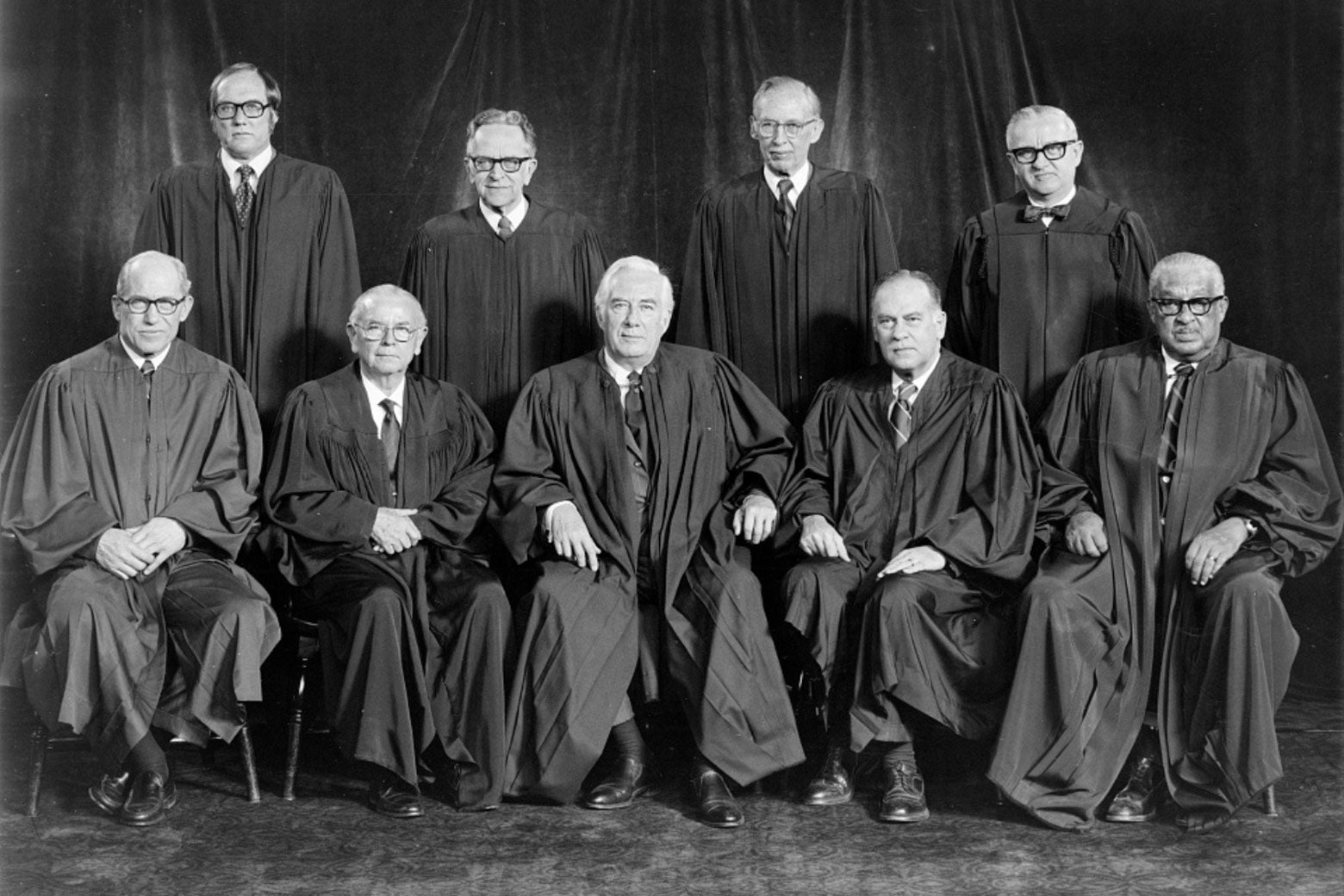 Nine men in robes pose for a photo.