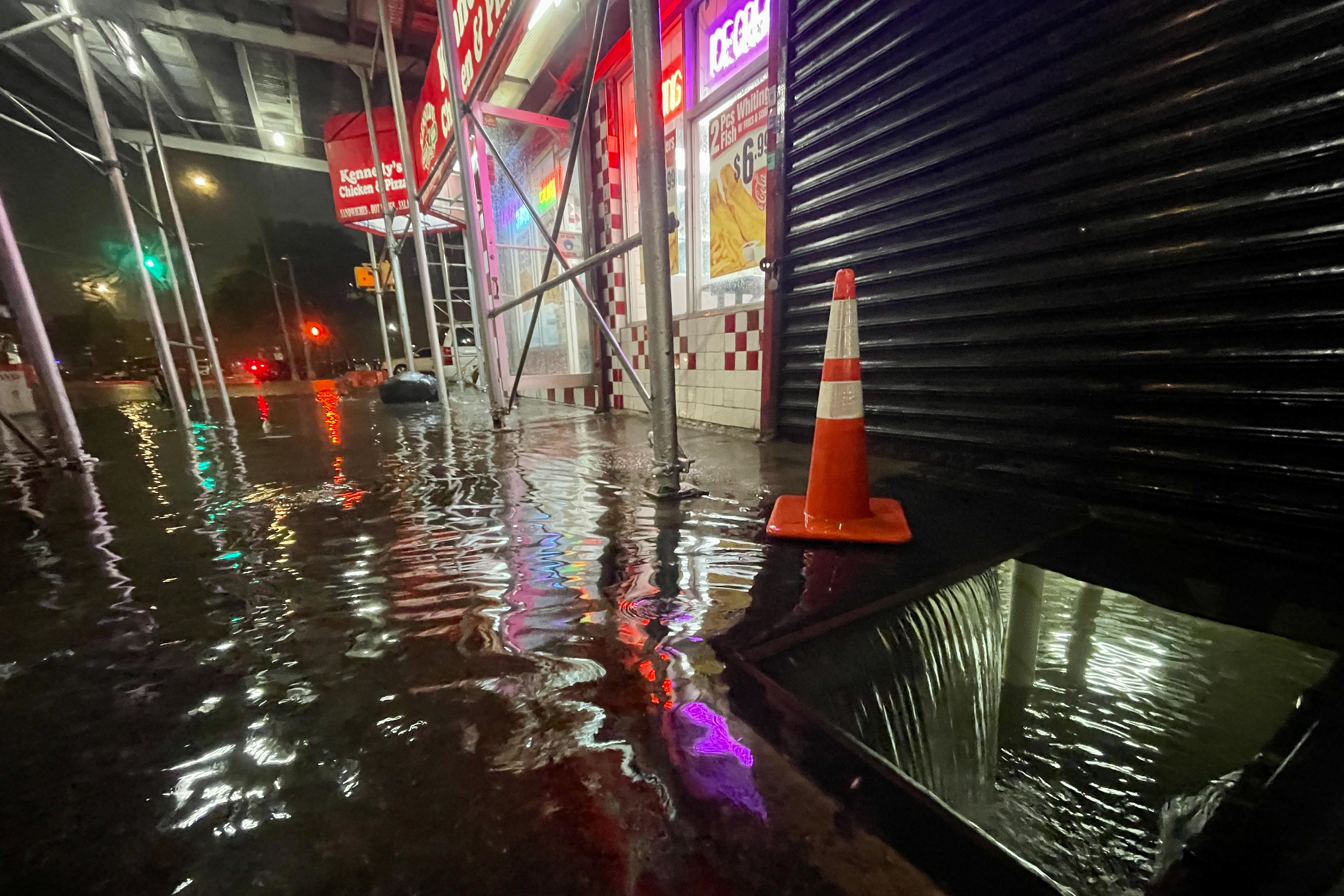 A street view of rain flooding the basement of a Kennedy Fried Chicken fast food restaurant.