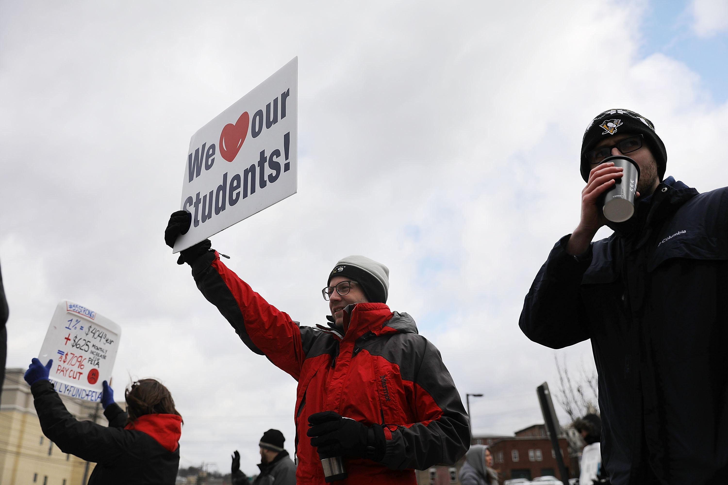 West Virginia teachers hold signs, saying things like, "We [heart] our students!," as they strike in Morgantown, West Virginia.
