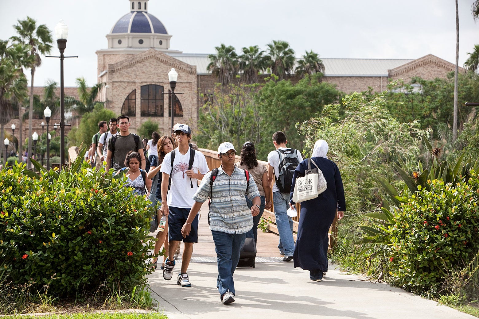 Students walk down a sidewalk on a campus.