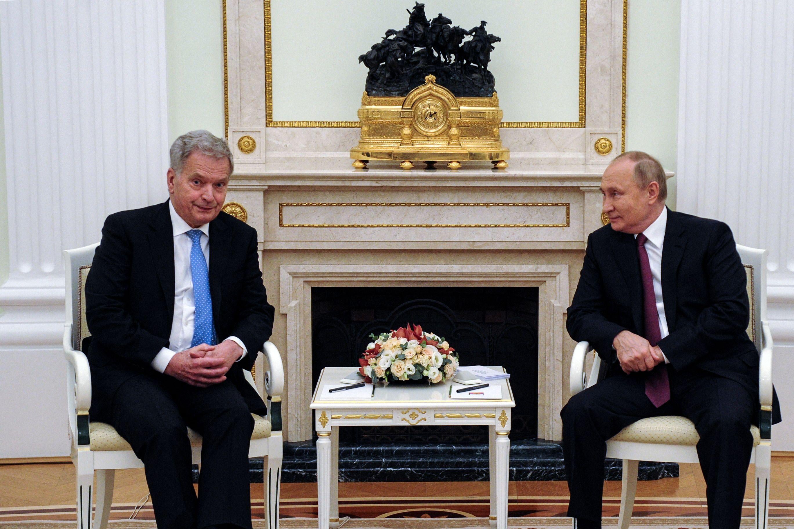 Putin and Niinisto sit in chairs smiling in a stateroom