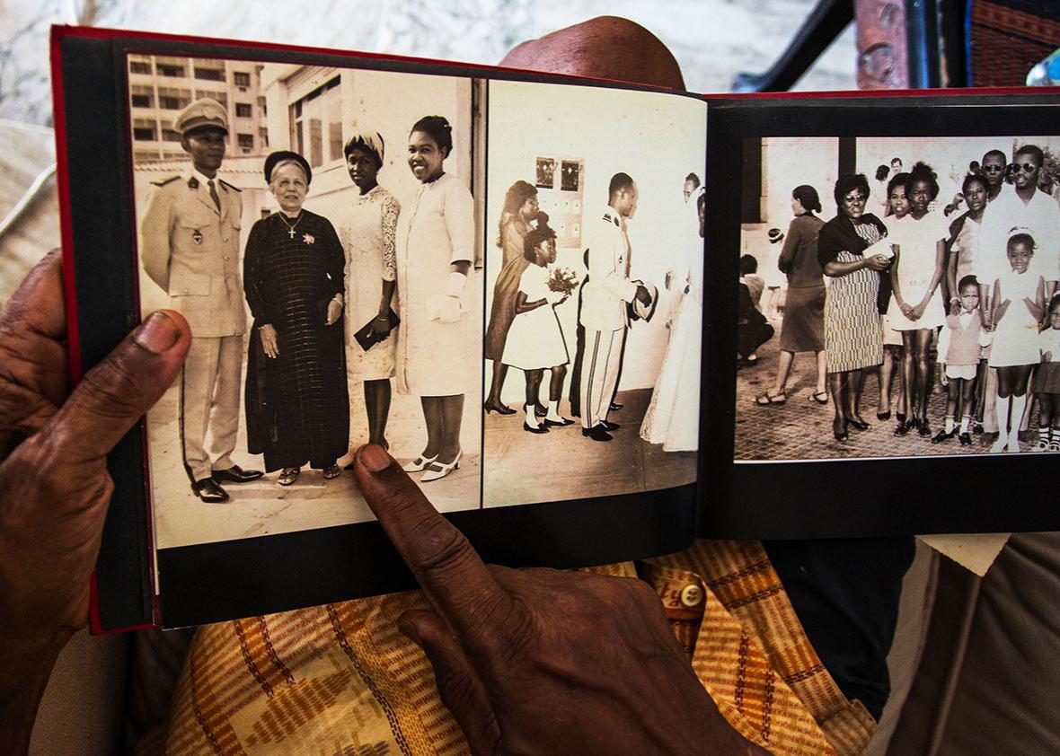 Jean Gomis points to a picture of himself, his mother, wife, and sister. Year unknown.