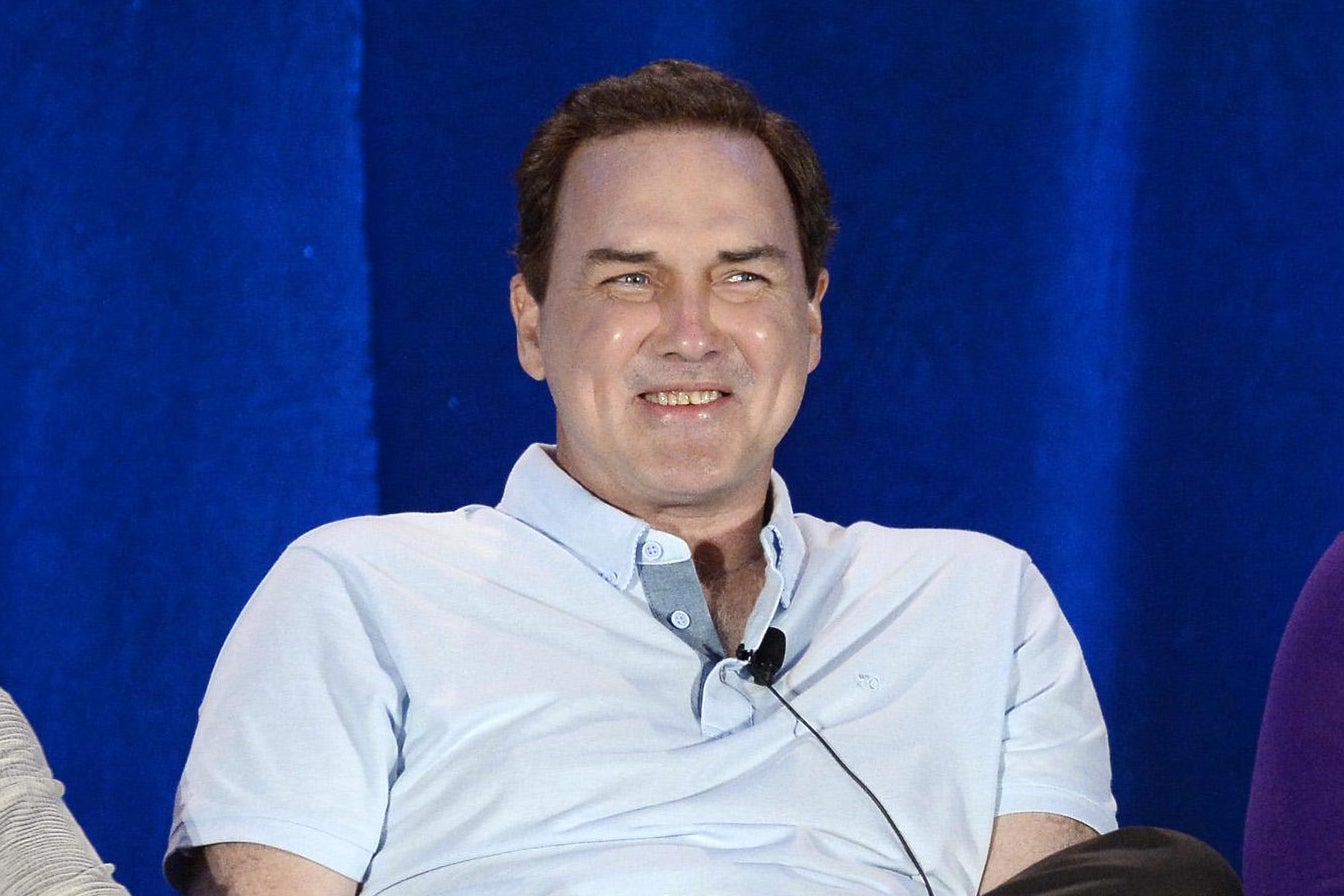 Norm Macdonald in a chair onstage for a panel discussion.