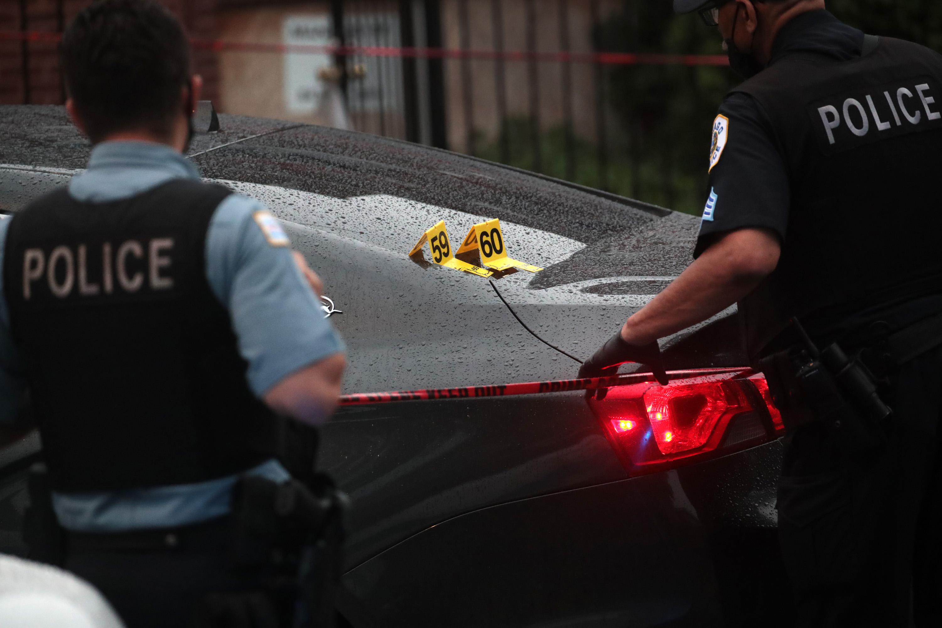 Shell casings labeled 59 and 60 rest on a bullet-riddled car as police investigate the scene of a shooting in the Auburn Gresham neighborhood of Chicago on July 21, 2020