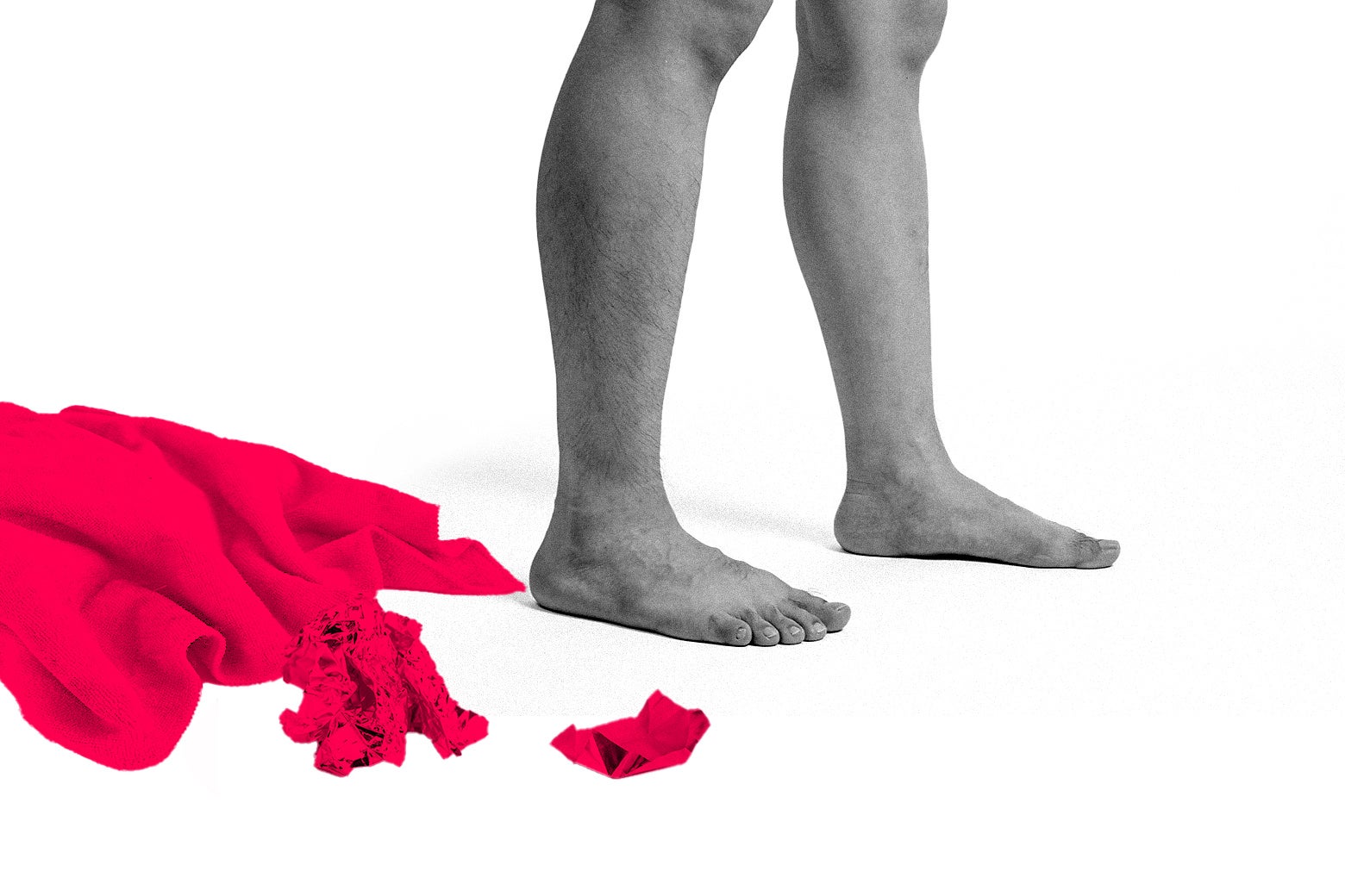 A person’s legs next to clothes on the ground.