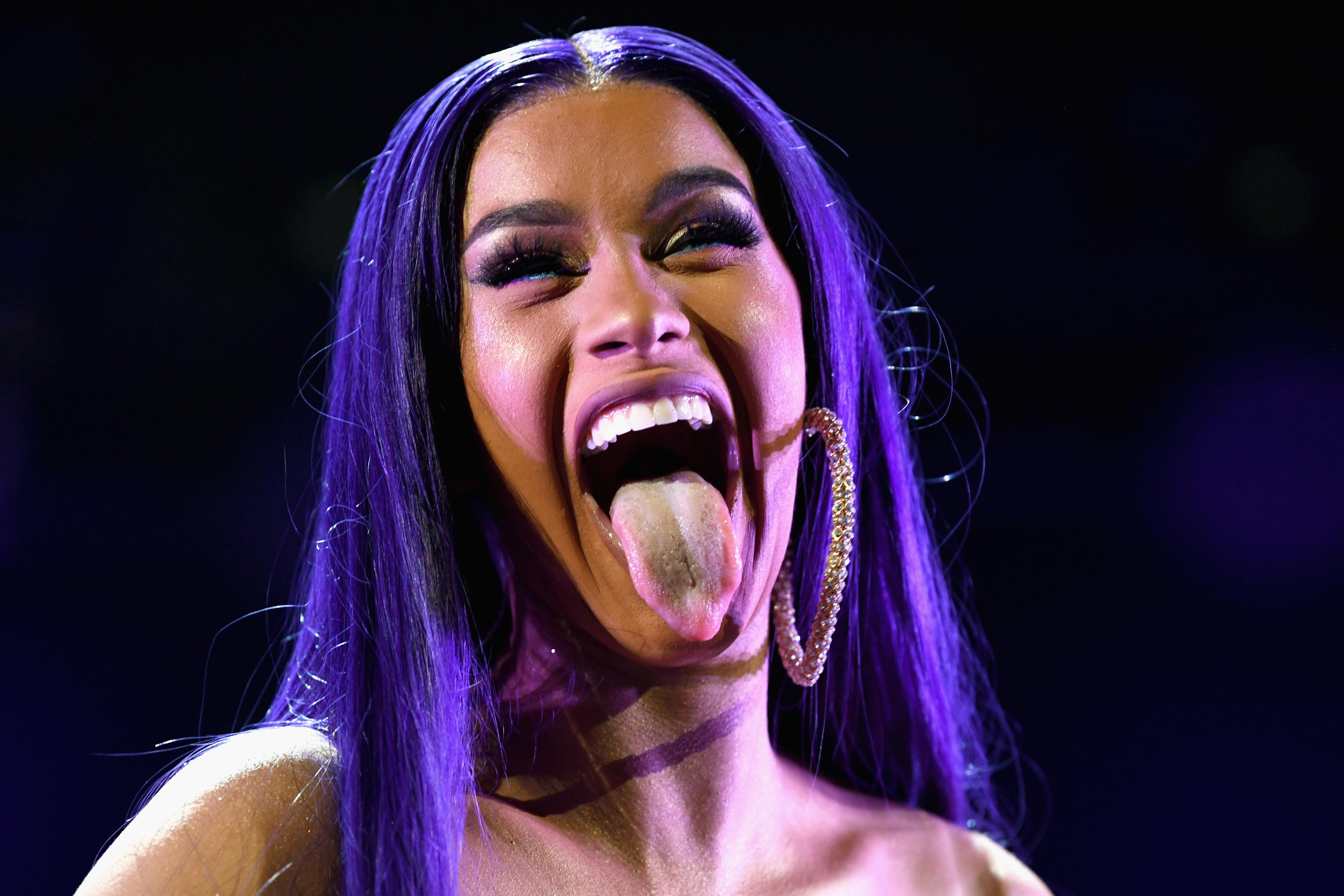 Cardi B sticking out her tongue on stage.