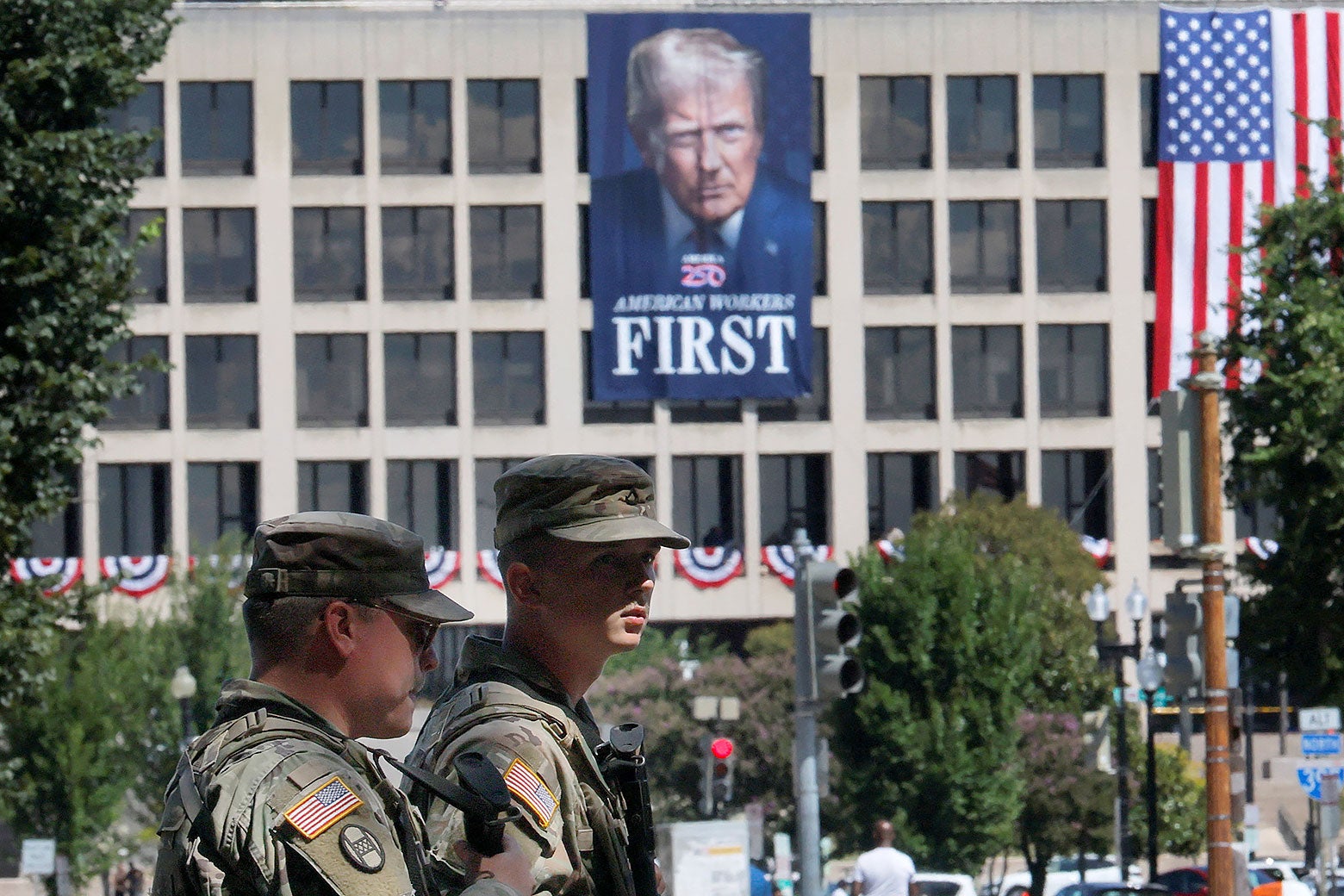 Truppen der Nationalgarde in Washington, D.C., hinter ihnen ein Gebäude mit einem riesigen Banner mit Trumps Gesicht
