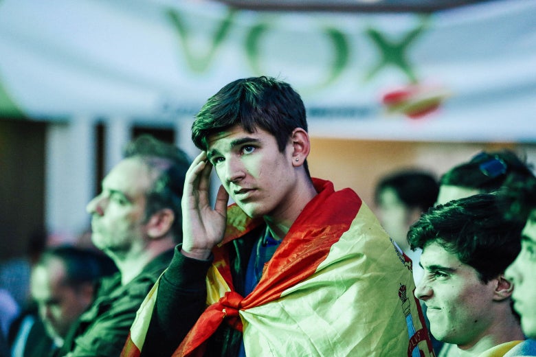 Supporters looking worried in front of a Vox party flag.