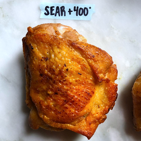A cooked chicken thigh with golden brown skin labeled Sear + 400 degrees.