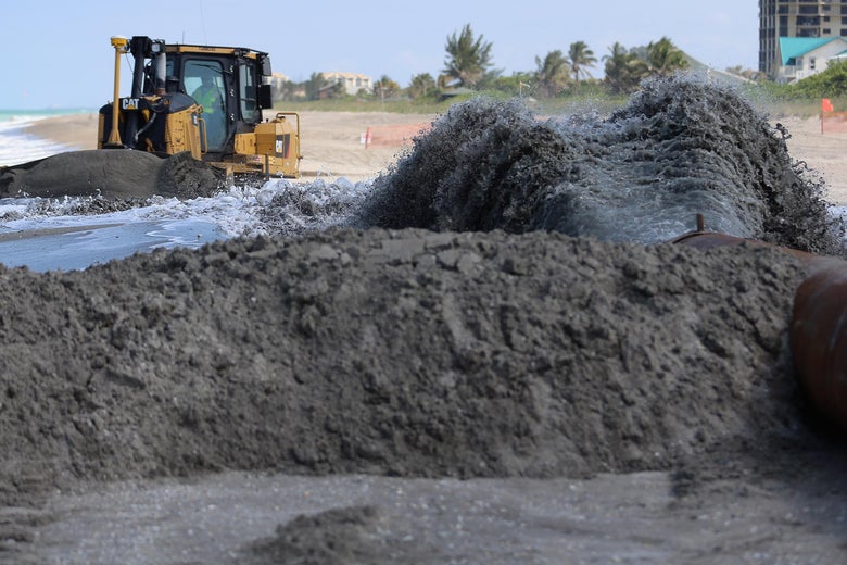 FORT PIERCE, FL - MAY 17: A bulldozer is used to push sand from a discharge pipe into place during a federally funded shore protection project by Great Lakes Dredge and Dock on May 17, 2013 in Fort Pierce, Florida. As cities along the East Coast prepare for the start of the hurricane season, officials say the area encompasing Fort Pierce beach has been in dire need of repair since Hurricane Sandy last year made worse an area already suffering significantly from erosion. Some experts say shore restoration projects can help reduce the physical and economic damage from waves, storm surge, and the resulting coastal flooding in a hurricane. (Photo by Joe Raedle/Getty Images)