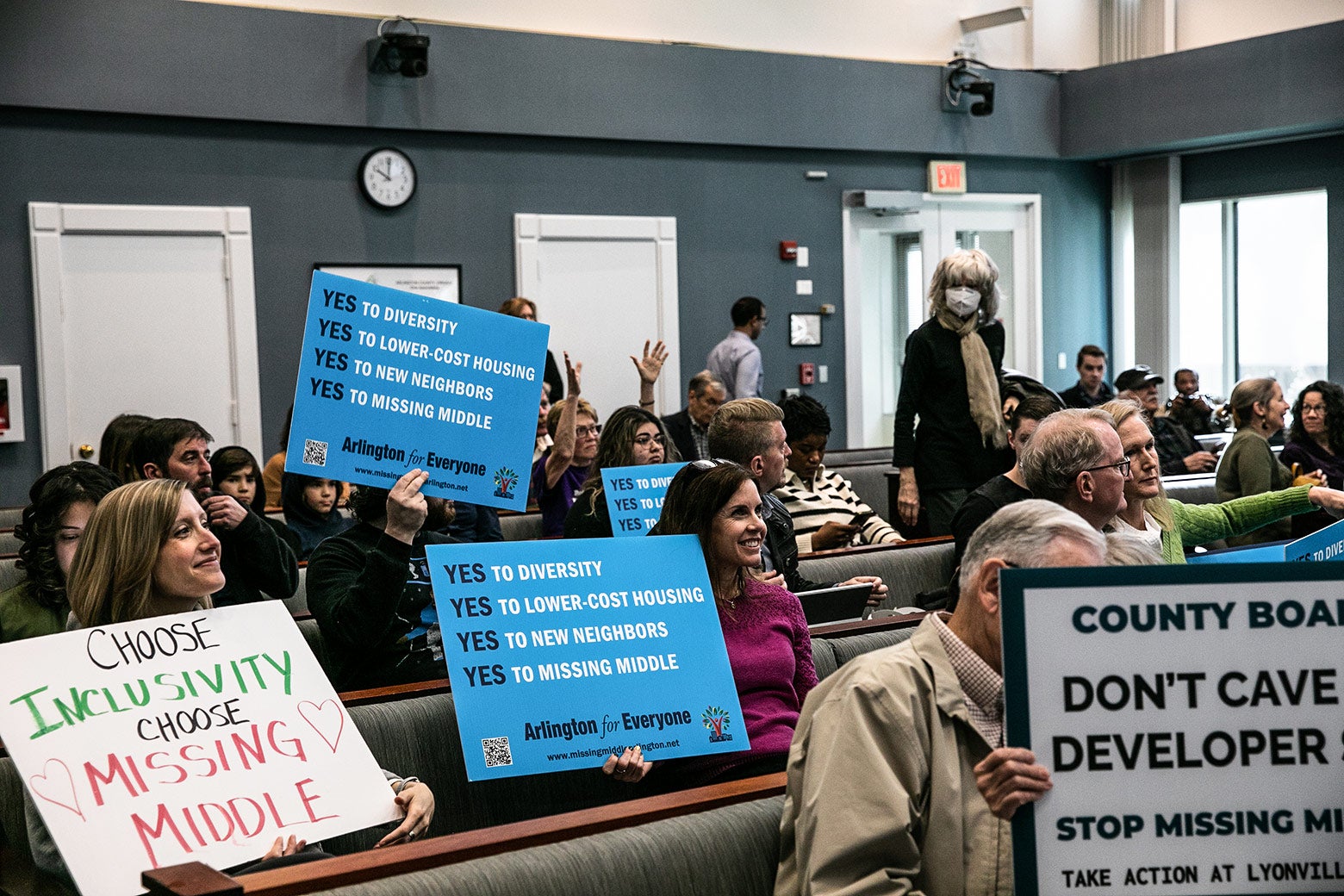 Several rows of pro–missing middle Arlington residents clutch signs that say "Choose Inclusivity: Choose Missing Middle" and "Yes to Diversity. Yes to Lower-Cost Housing."