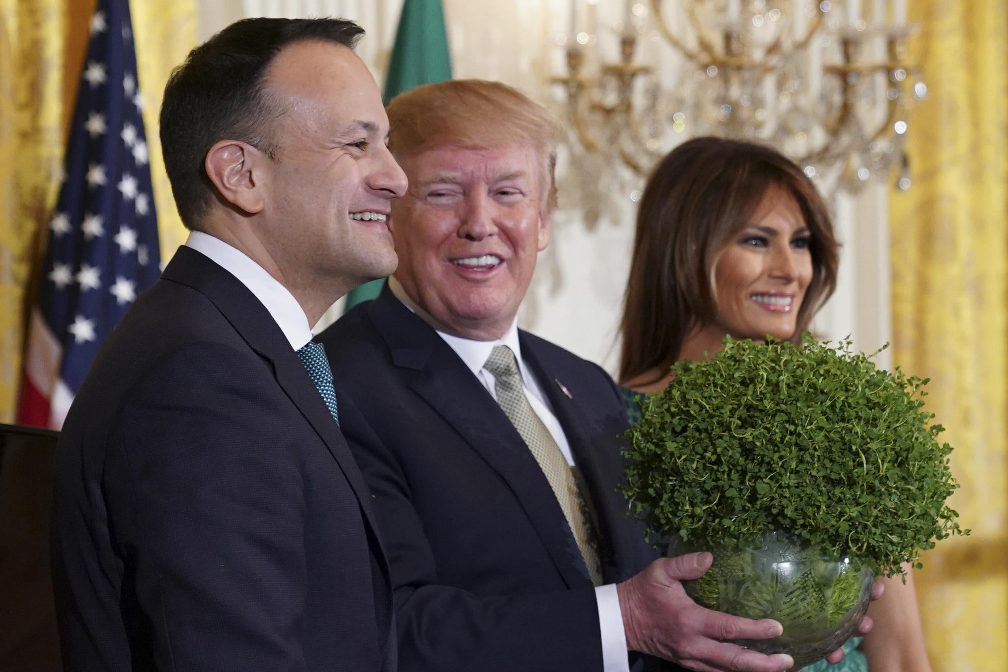 President Donald Trump picks up a bowl of shamrocks as Ireland's Prime Minister Leo Varadkar and First Lady Melania Trump look on in the East Room of the White House March 15, 2018 in Washington, D.C.