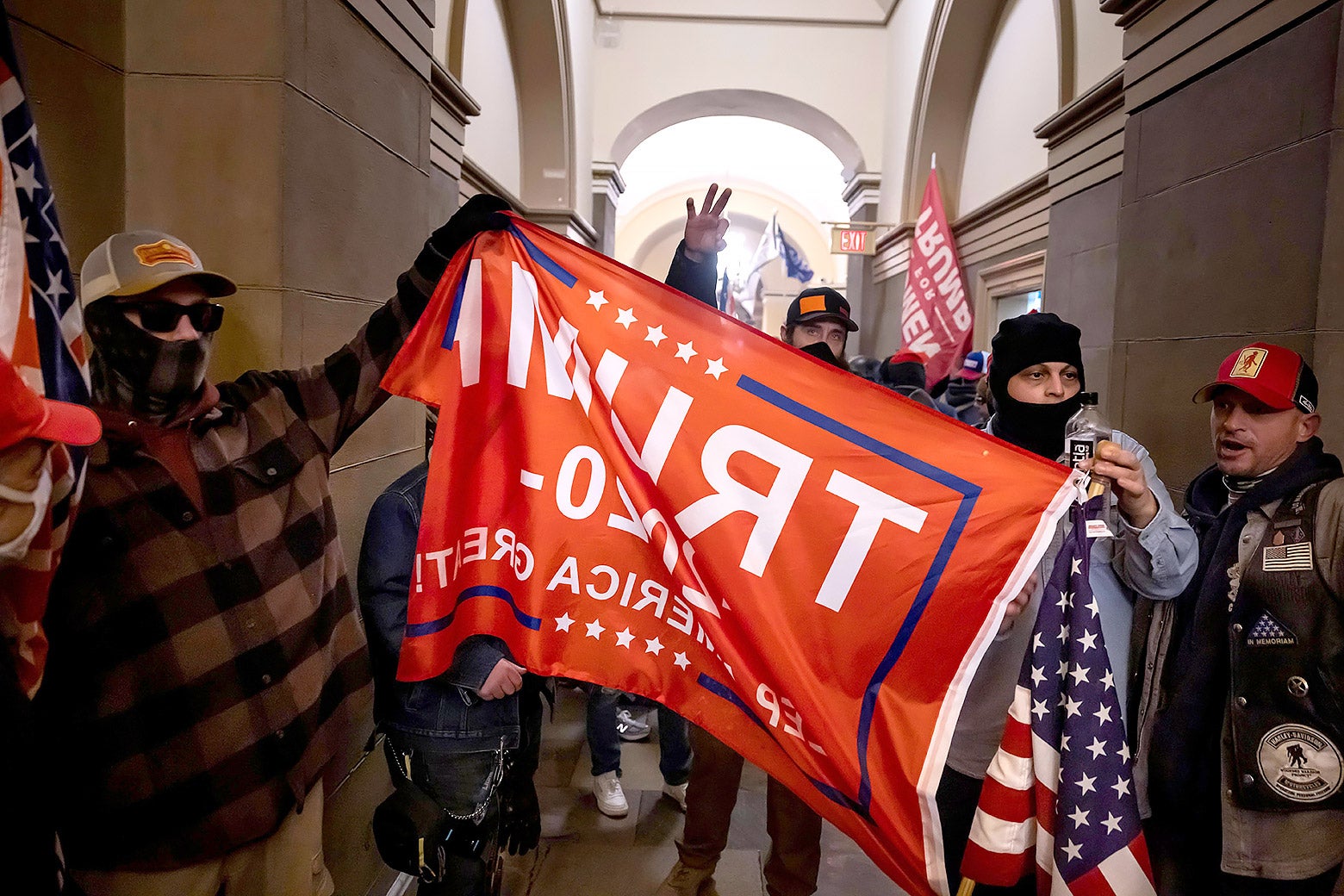 A group of January 6 insurrectionists holding a Trump flag inside the Capitol.