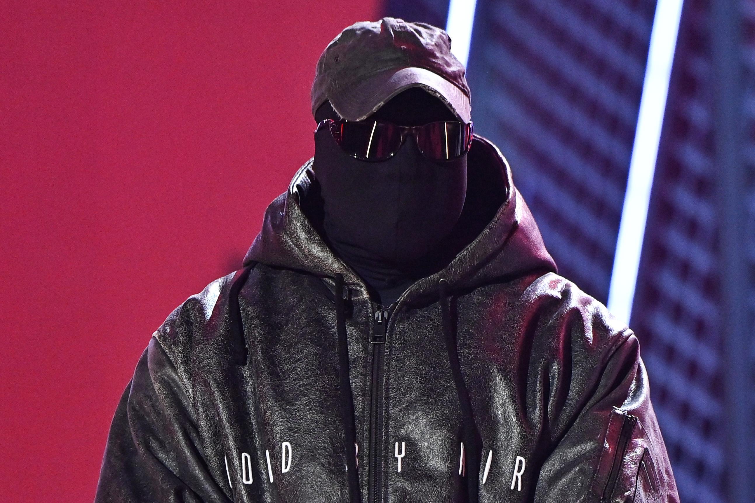 Kanye "Ye" West in a hoodie, face mask, cap, and sunglasses
