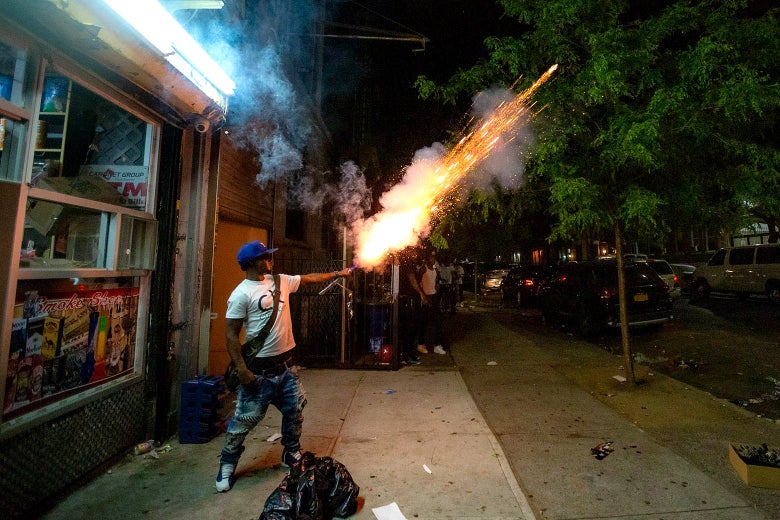 A man in Brooklyn New York holds a firework stick in his hands as it explodes.
