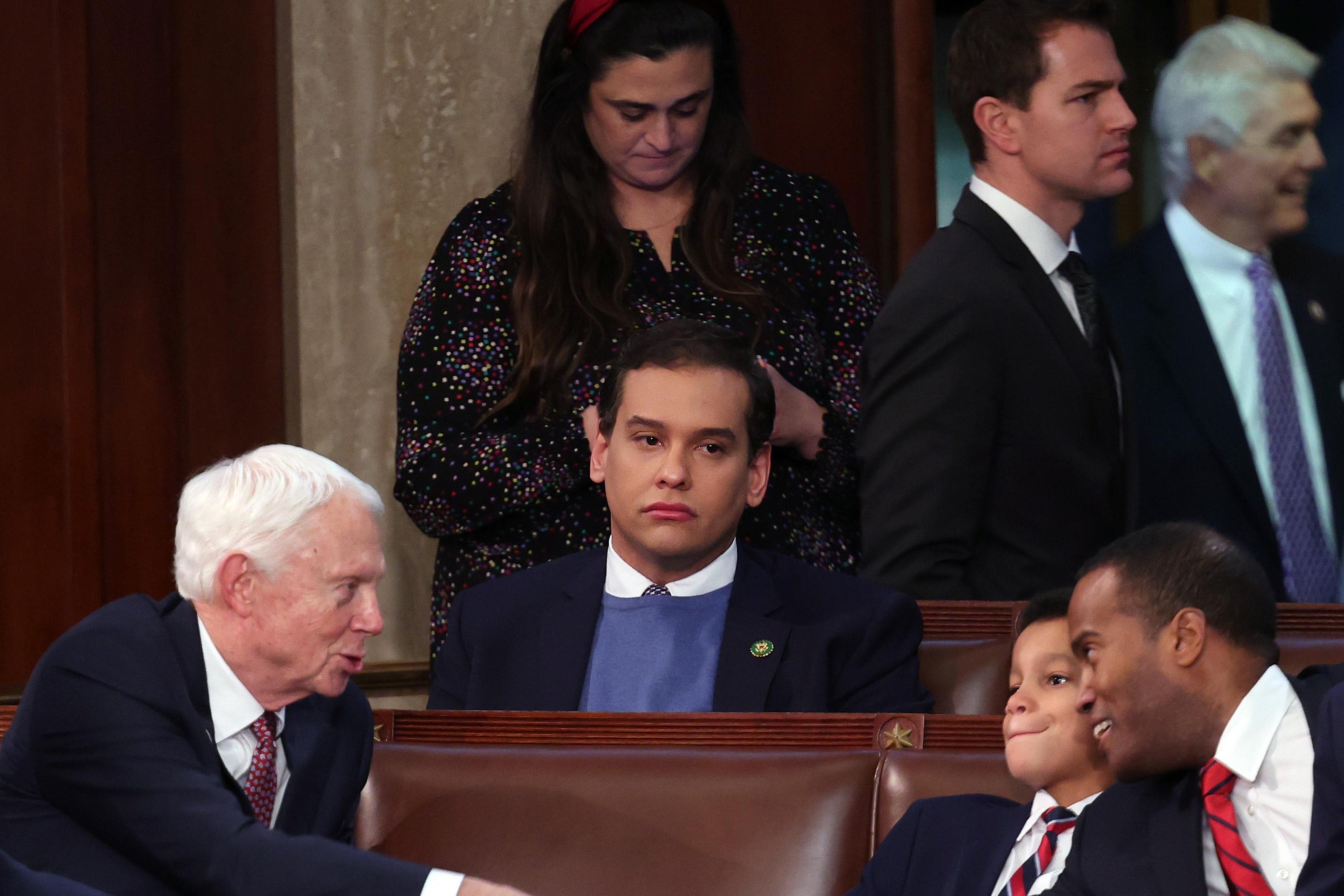 George Santos, an incoming House rep. from New York who lied about nearly every aspect of his background and biography, looking forlorn, in the midst of other people shaking hands, in Congress.