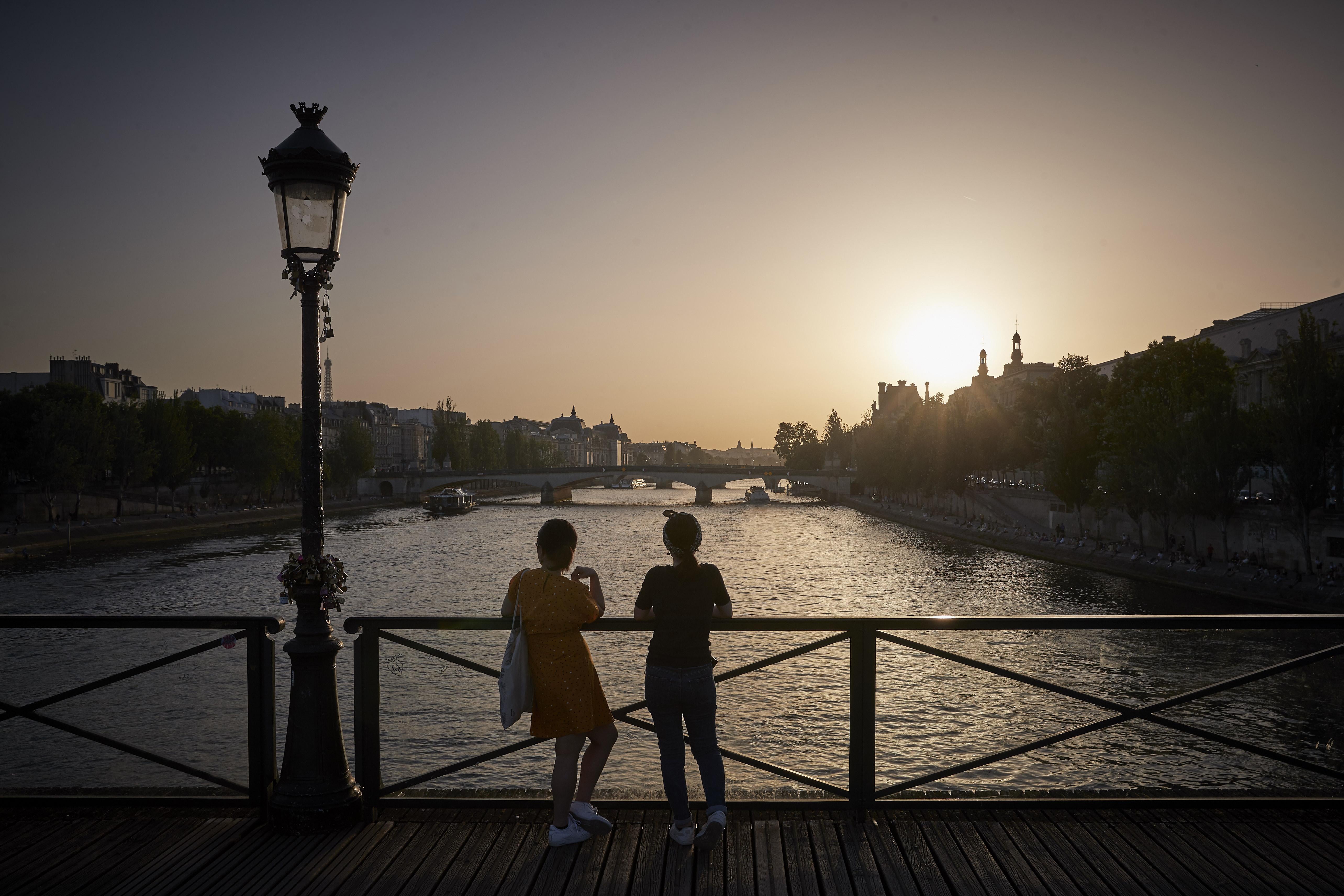 PARIS, FRANCE - JUNE 18: Parisians watch the sun set from Pont des Arts bridge after a day of soaring temperatures of close to 40°C in what is expected to be a new record for the hottest June day in the city on June 18, 2022 in Paris, France. Outdoor public events across France have been cancelled as countries across Europe face high temperatures caused by the mass of hot air moving from north Africa, causing health risks as well as wild fires and energy shortages.