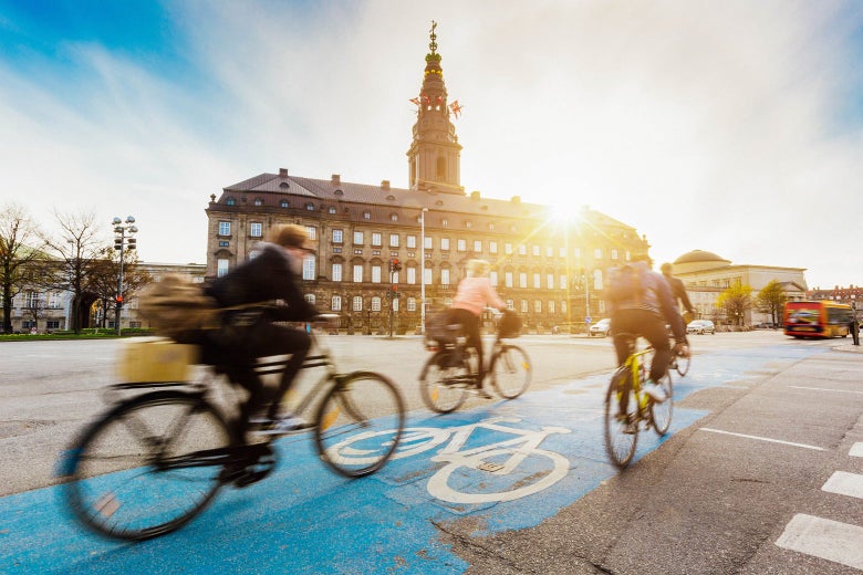 Cyclists bike in Copenhagen, with Christiansborg Palace in the background.