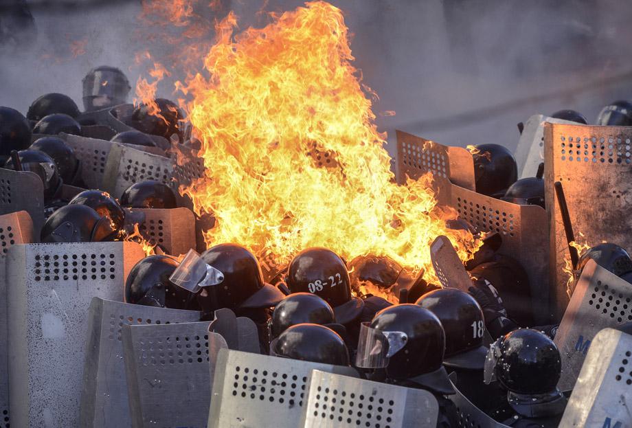 Government police catch fire from Molotov cocktails hurled by protesters as they stand guard during clashes in Kiev on Feb. 18, 2014.