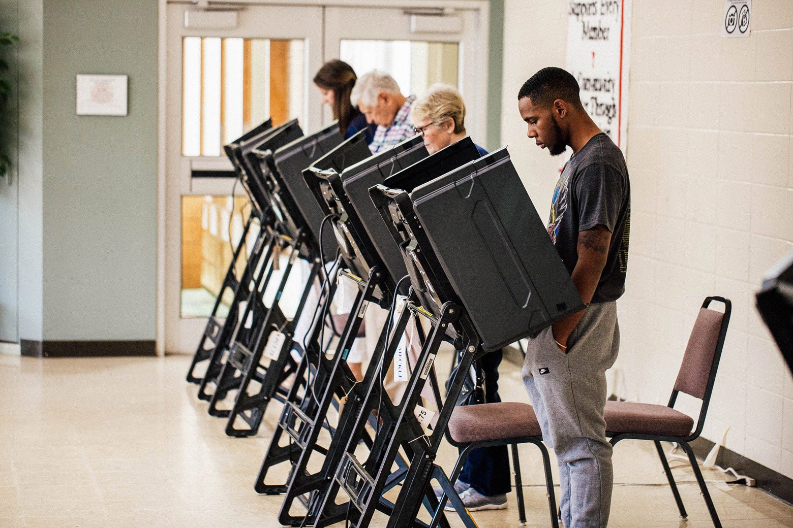 A row of voters voting at booths.