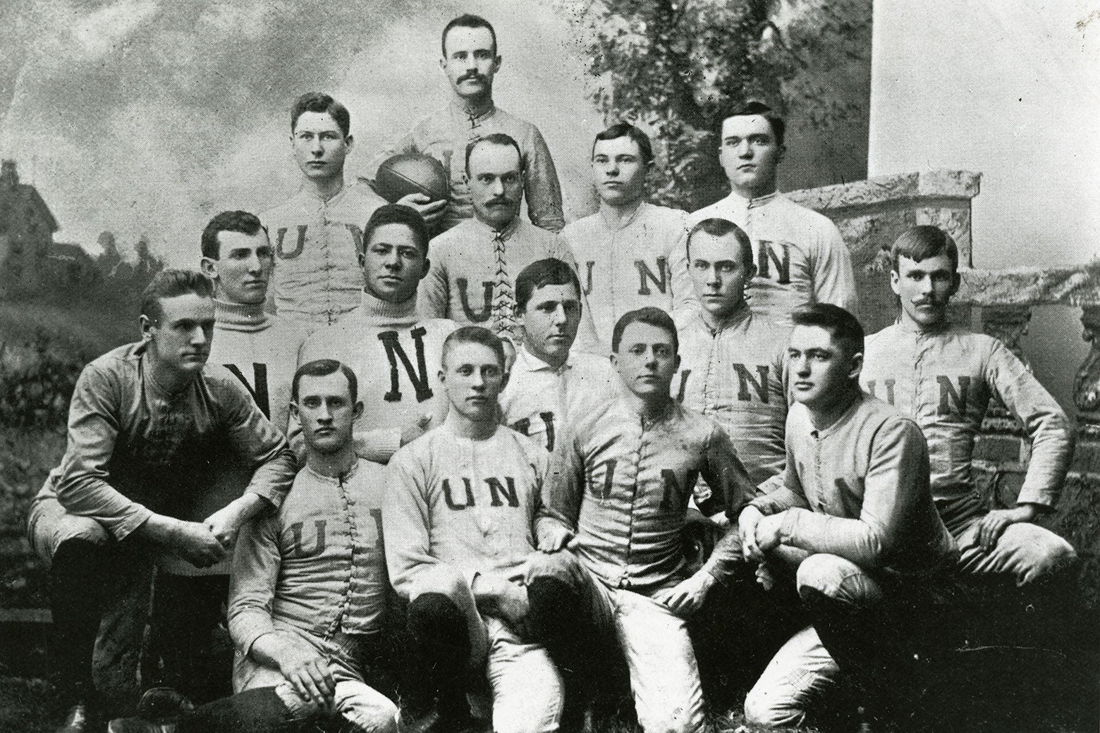 Black-and-white photo of an old-fashioned football team posing for the camera.
