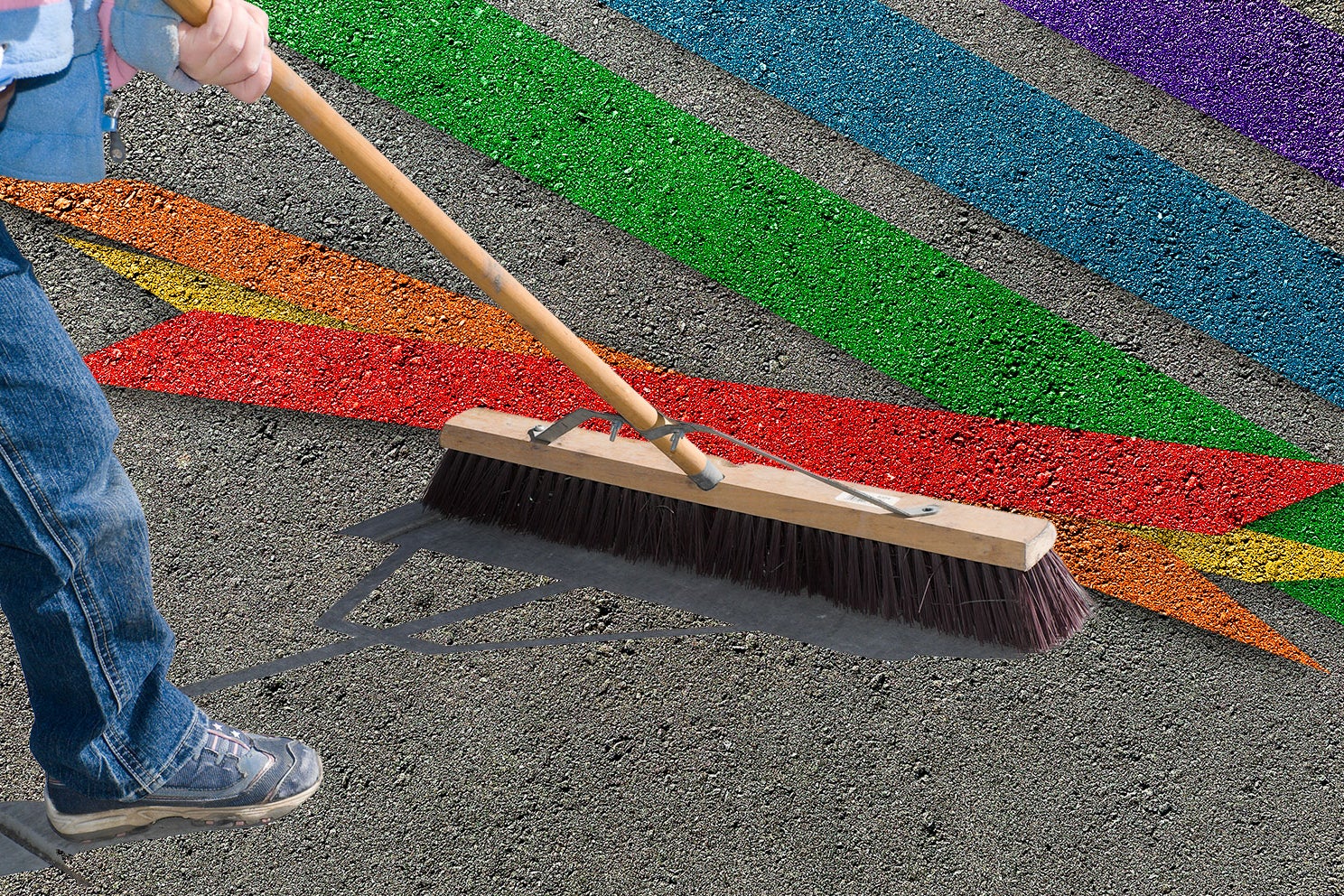 Street worker brushing away a rainbow chalk art at a crosswalk. 