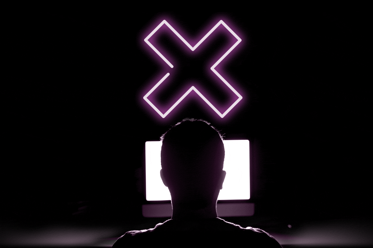 A man's back at a computer with a neon X flashing over his head.