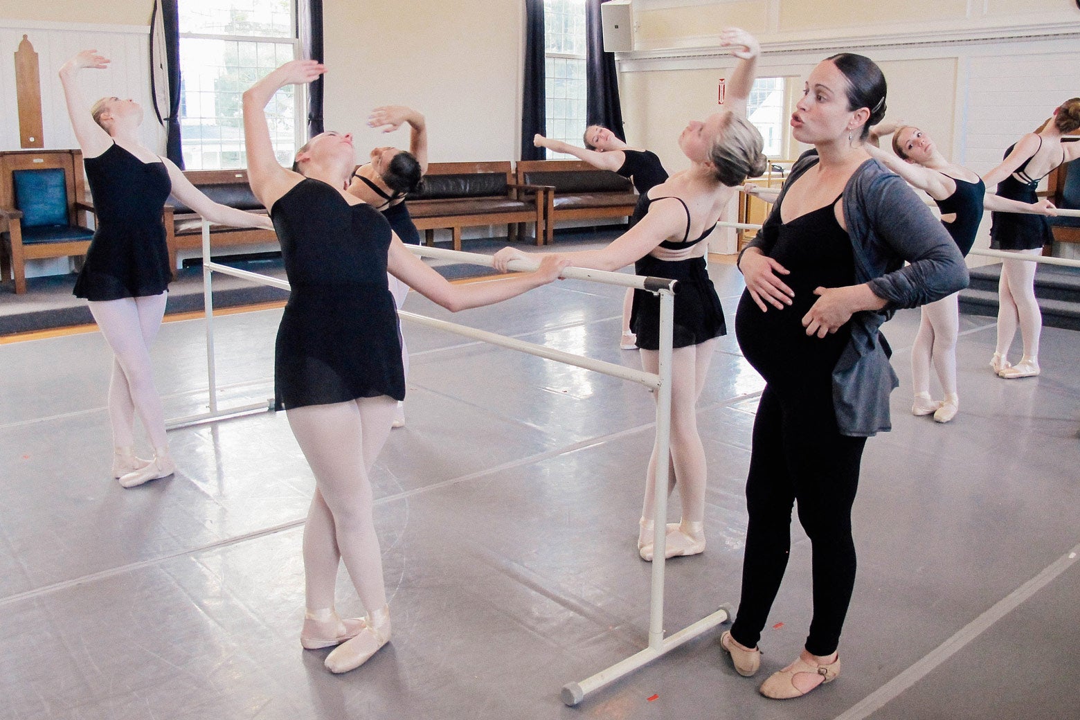 Anecia teaches students on the bar in a ballet class.