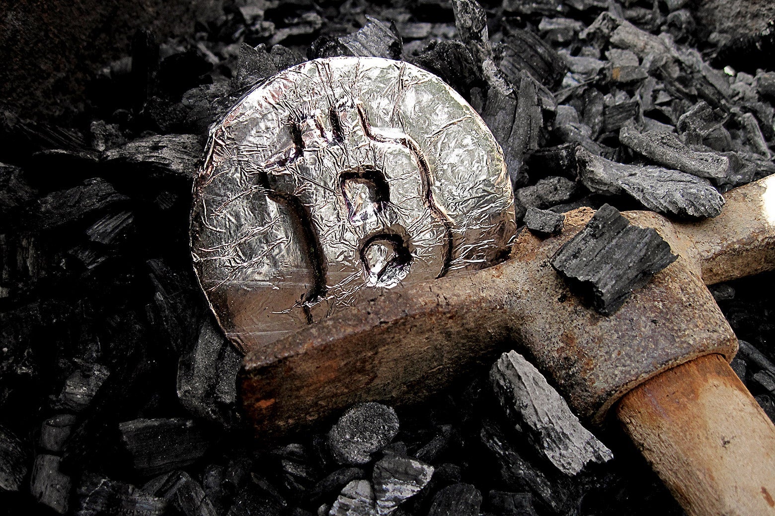 A miner's ax next to a medallion with the Bitcoin logo on it.