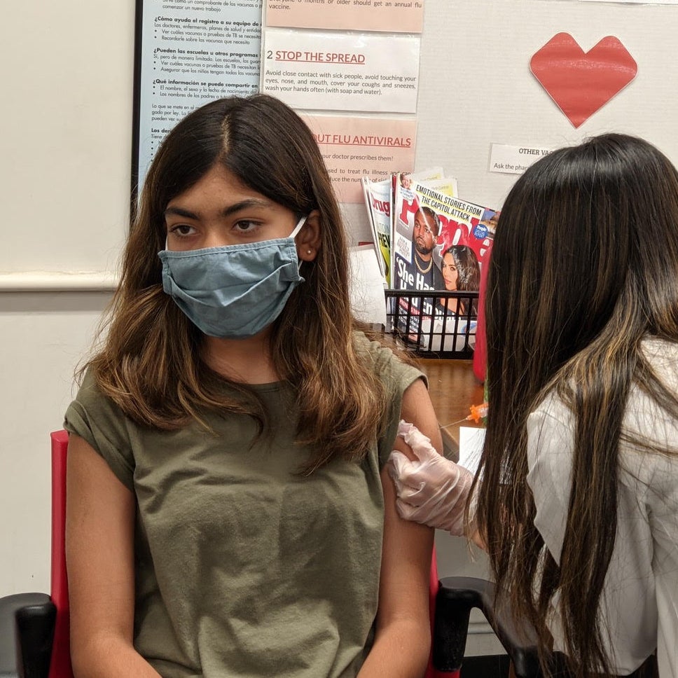 A girl wearing a mask received a vaccine.