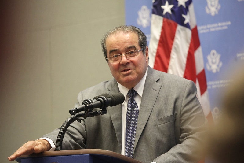 Justice Antonin Scalia speaks at a podium with an American flag behind him