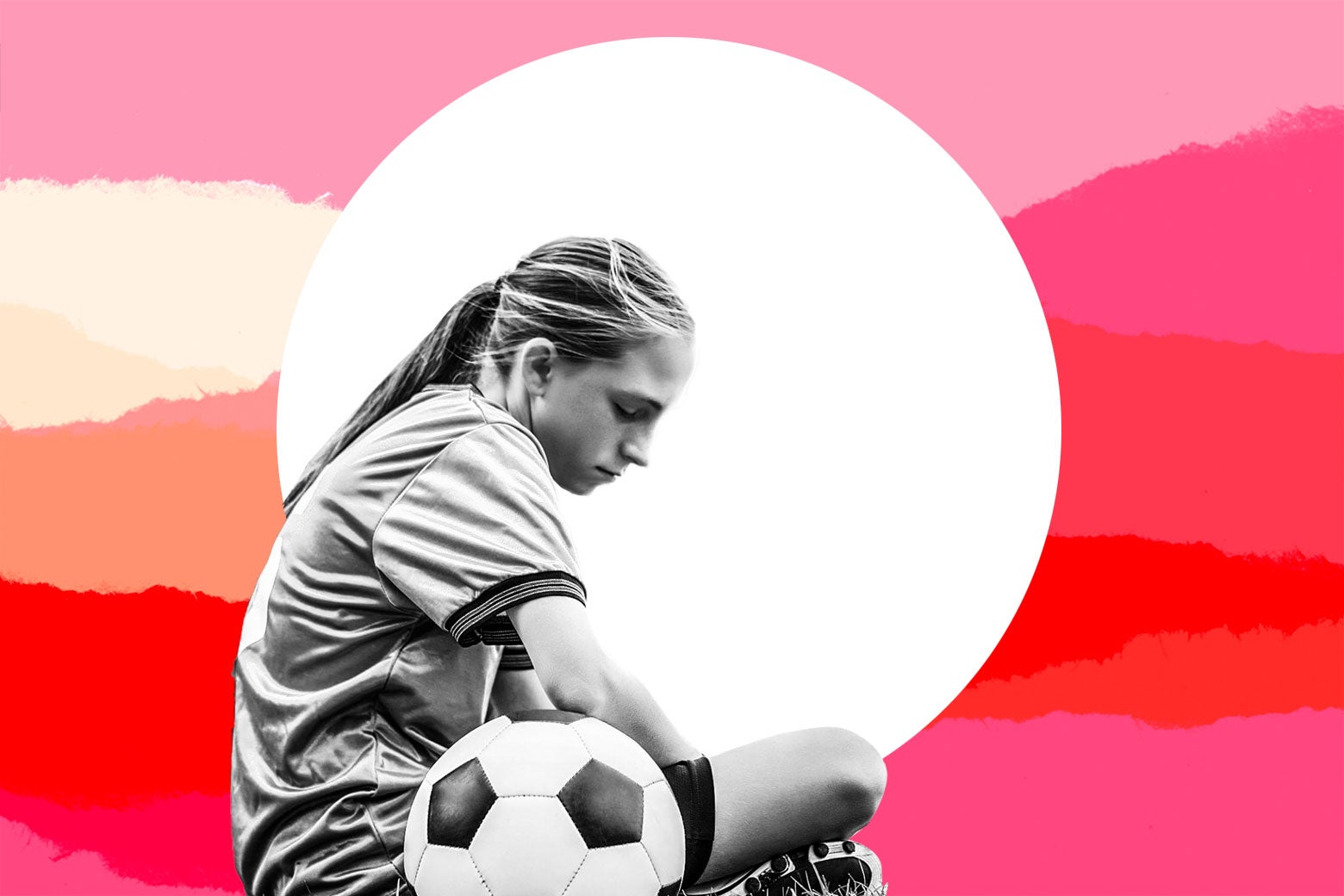 A girl in a soccer uniform sitting next to a soccer ball, looking glum.