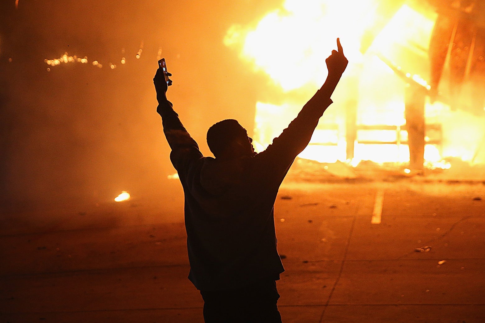 A demonstrator celebrates as a business burns during rioting following the grand jury announcement in the Michael Brown case on Nov. 24, 2014 in Ferguson, Missouri.
