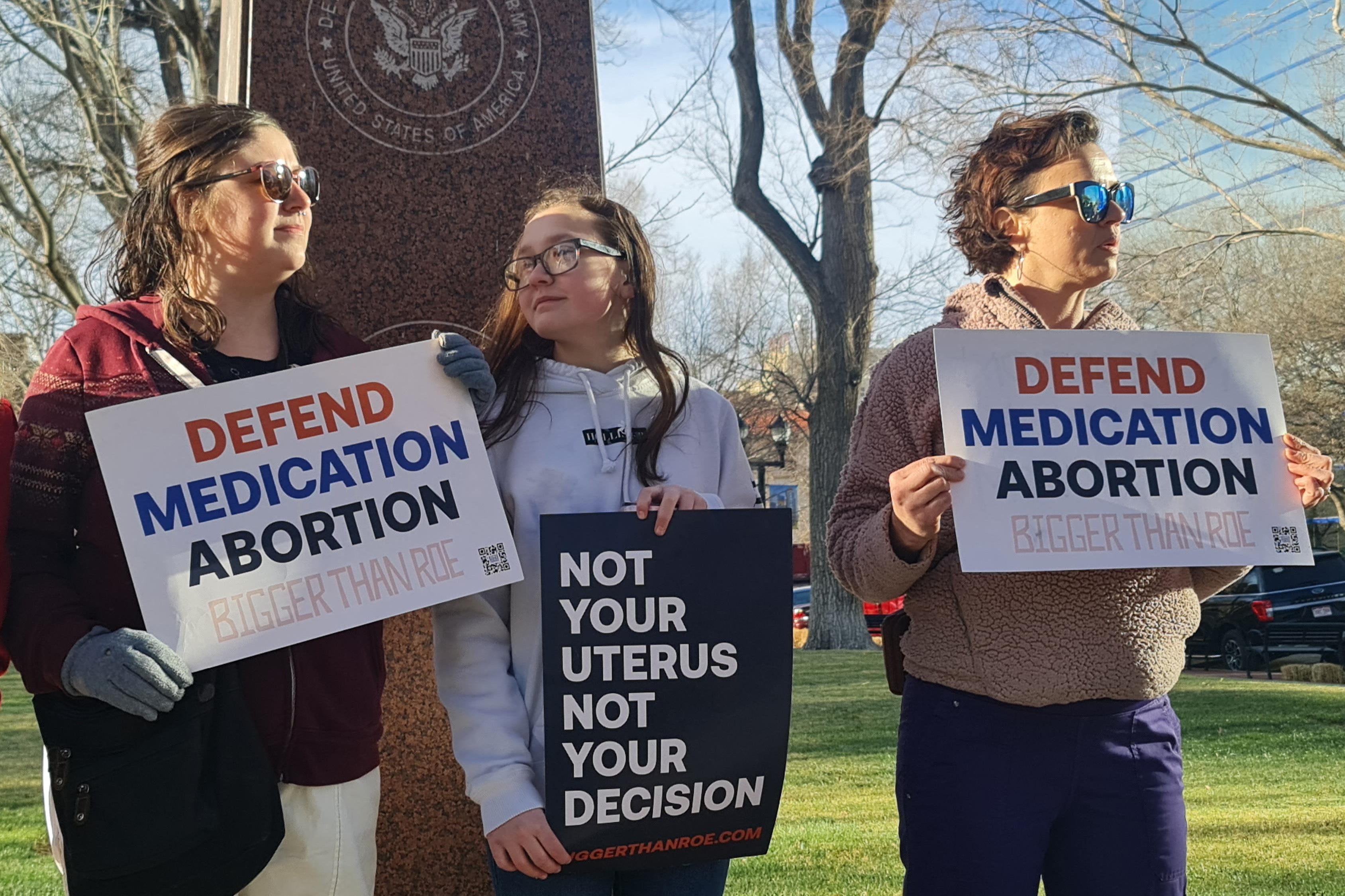 Women hold signs saying "Defend Medication Abortion"and "Not Your Uterus Not Your Decision" and "Bigger Than Roe."