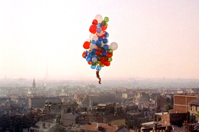 In a still from The Red Balloon, Pascal Lamorisse glides above a city, kept aloft only by the cloud of balloons he's holding onto.