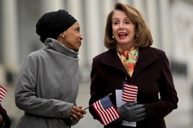 Rep. Ilhan Omar talks with Speaker of the House Nancy Pelosi on the east steps of the U.S. Capitol. Both women are holding small American flags.
