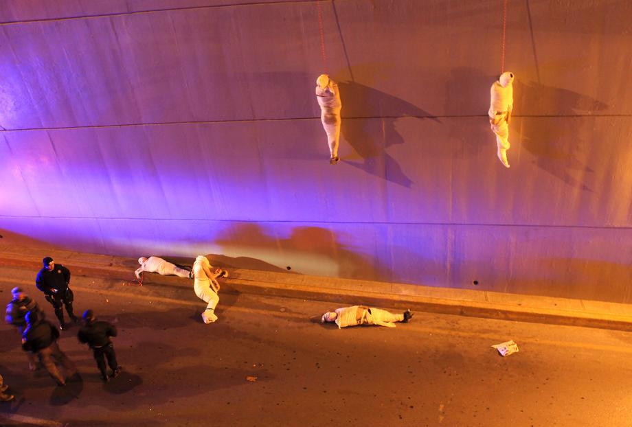 Police and forensic technicians stand near the wrapped bodies of two unidentified men hanging from an overpass as three more bodies lie on the ground in Saltillo, Mexico, on March 8, 2013. Five corpses wrapped head to toe in white sheets were found early Friday on a highway in the northern Mexican city of Saltillo, victims of suspected gang-related slaying. The attorney general's office of Coahuila state said three of the bodies were hung by rope from a bridge and two were on the ground. All were male and lacked identification.