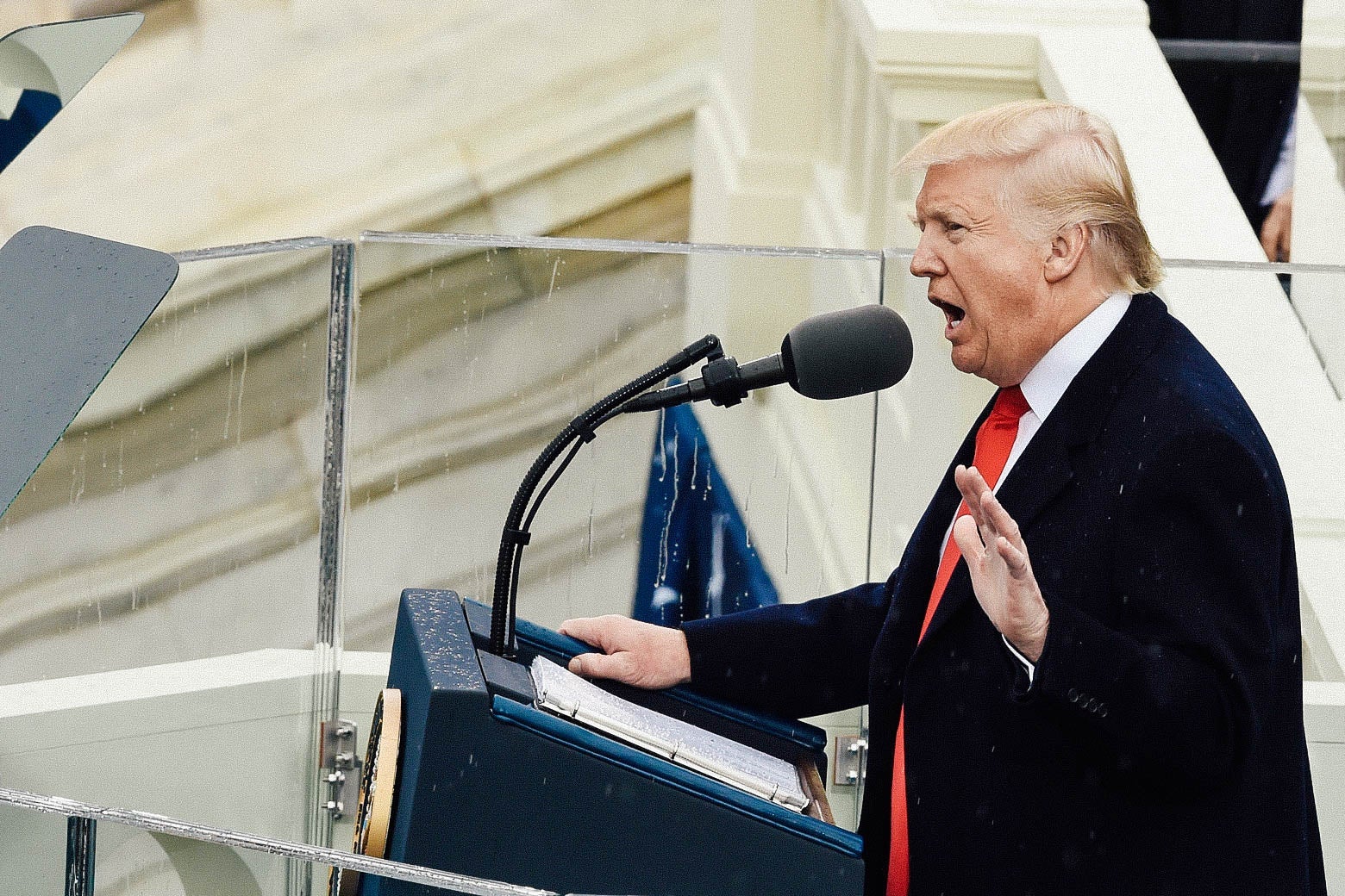 Donald Trump speaks into a large microphone on a podium.