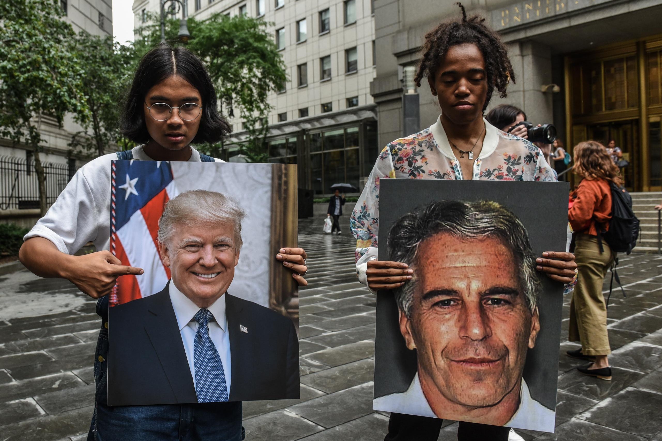 Protesters hold up photos of Donald Trump and Jeffrey Epstein.
