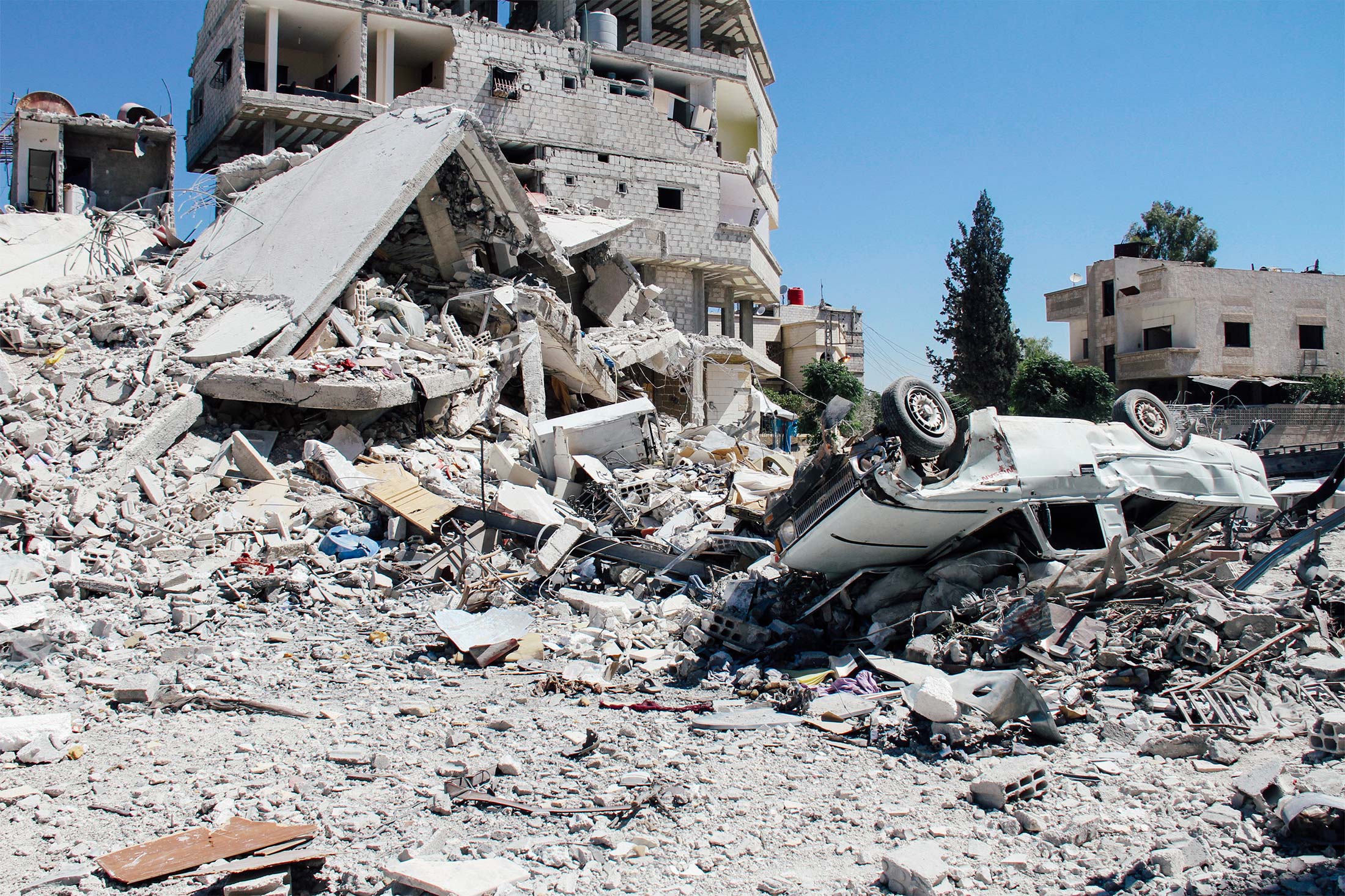 A destroyed building and a flipped-over car.