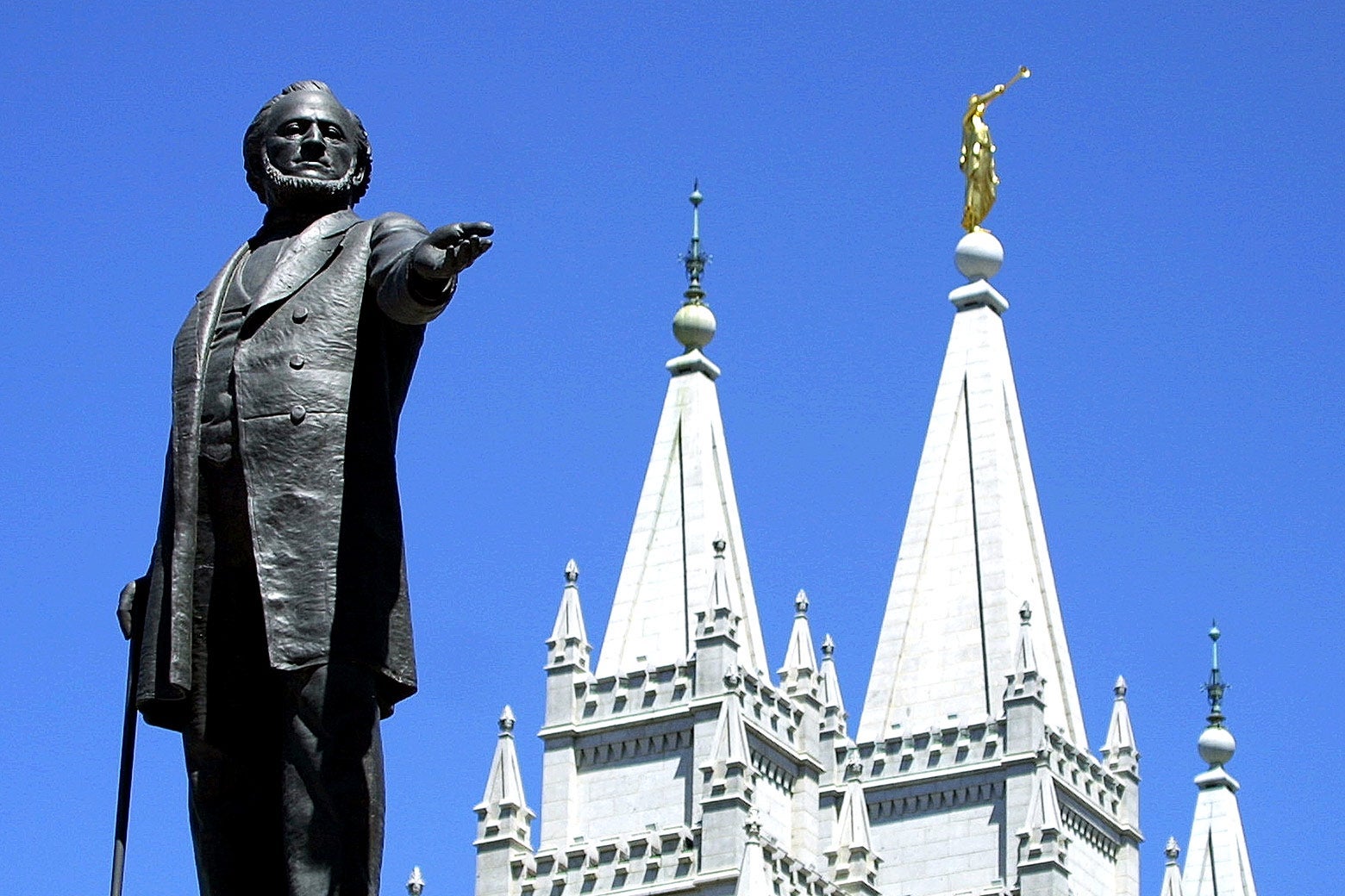 A statue of Brigham Young is seen beside a regal building.